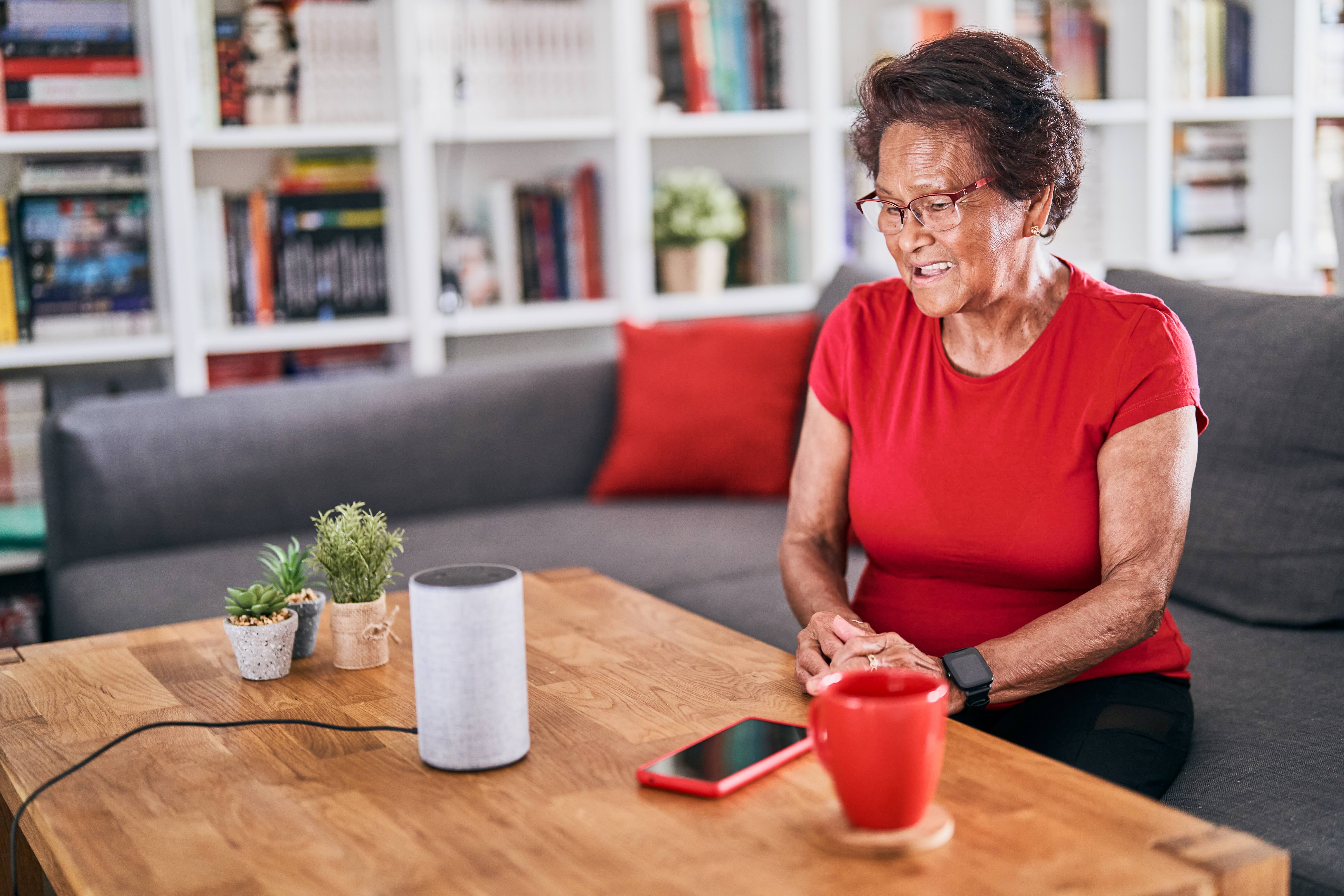 Older woman at table with smart phone and speaker