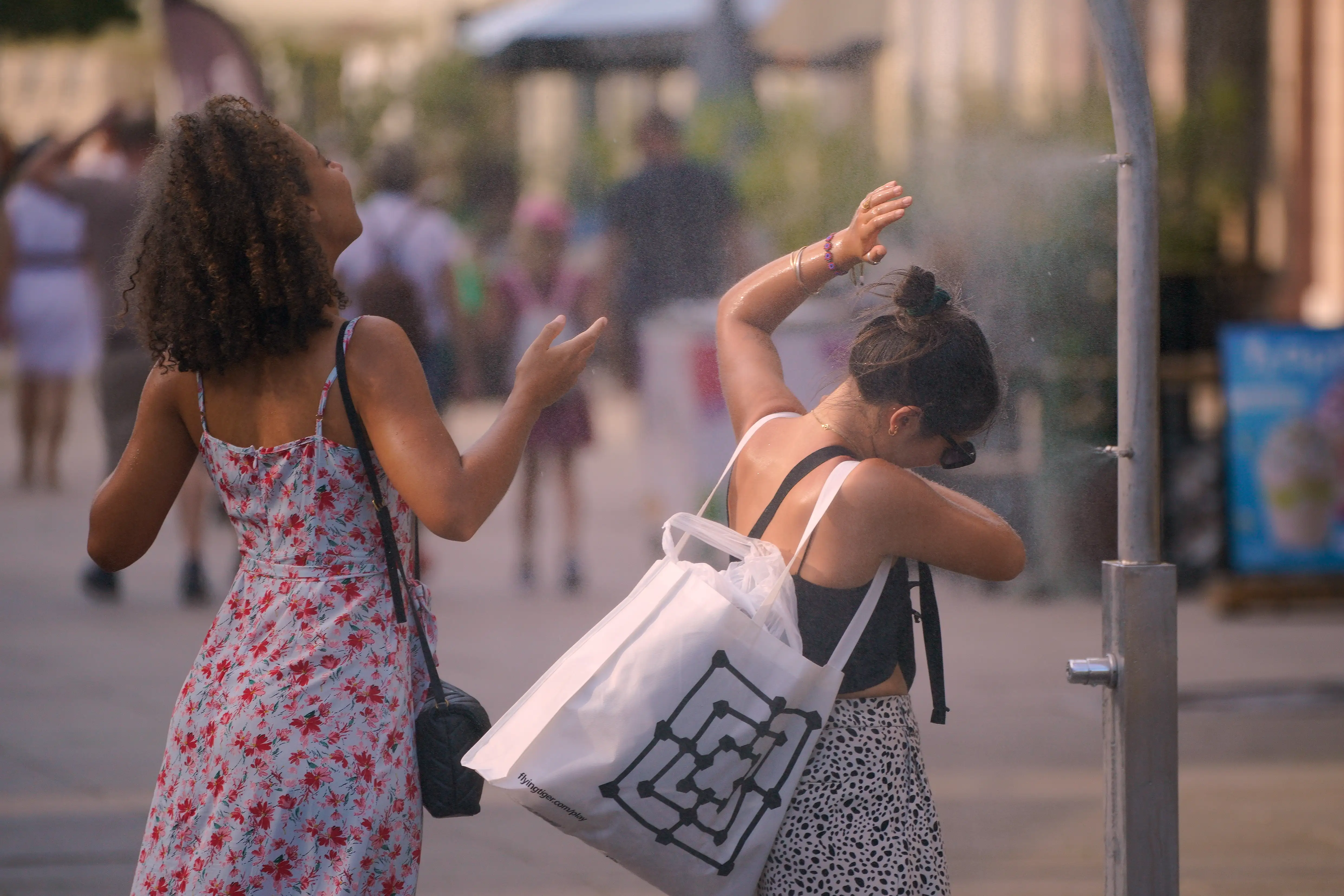 A group of people cool off at a misting station during a heatwave 