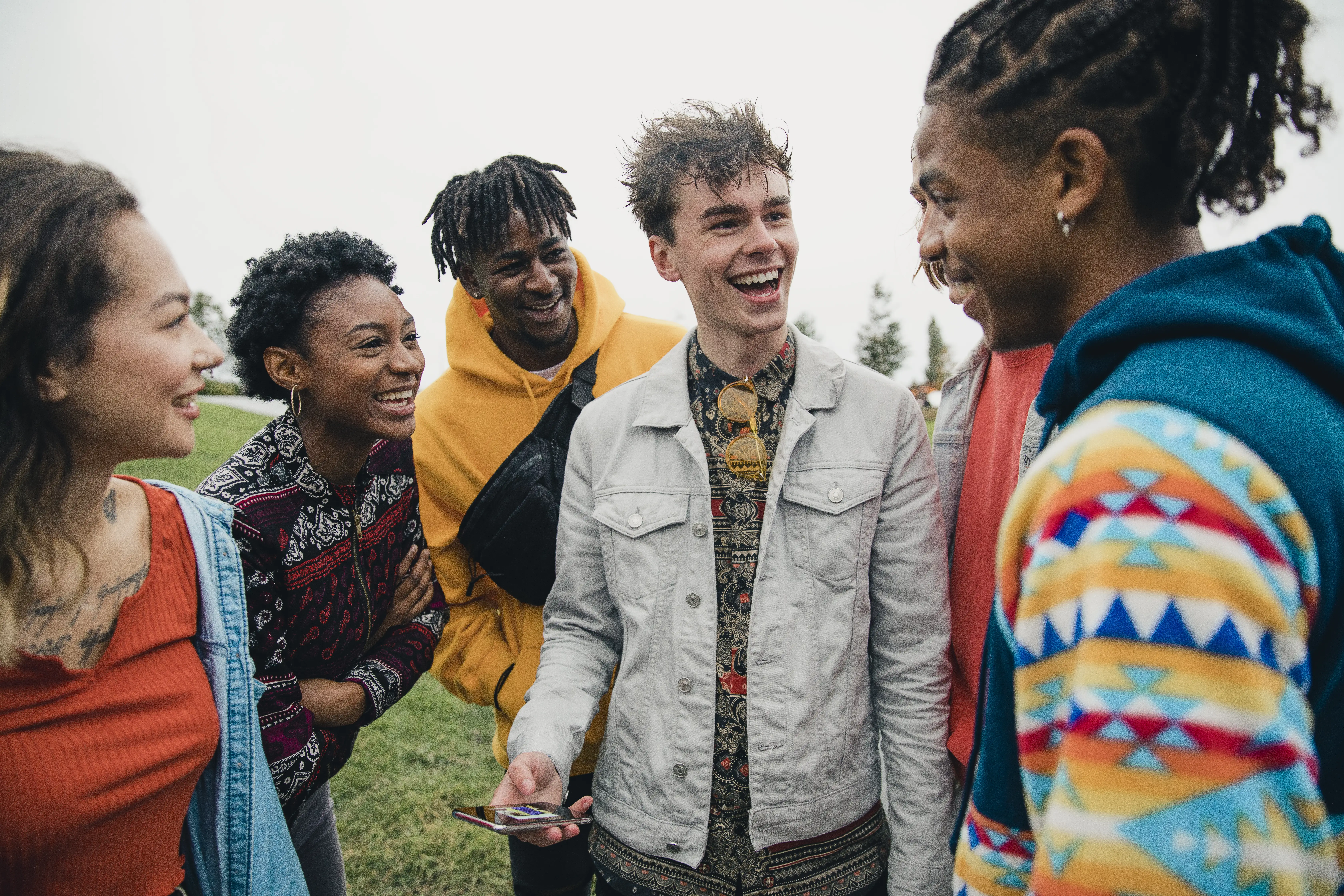 A small group of diverse young friends are hanging out in a public park