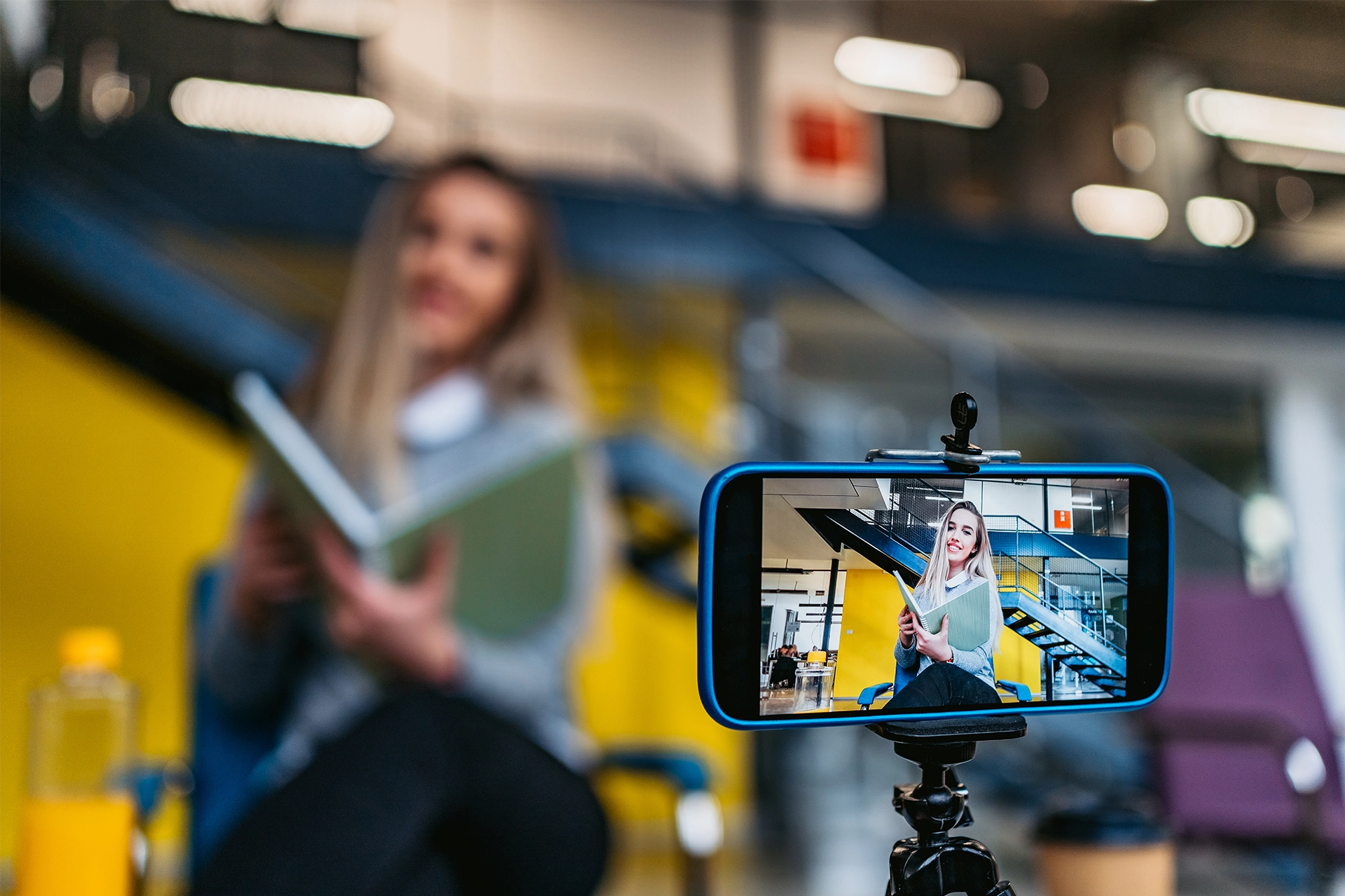 Woman reading a phone, filming herself using an iPhone on a small tripod