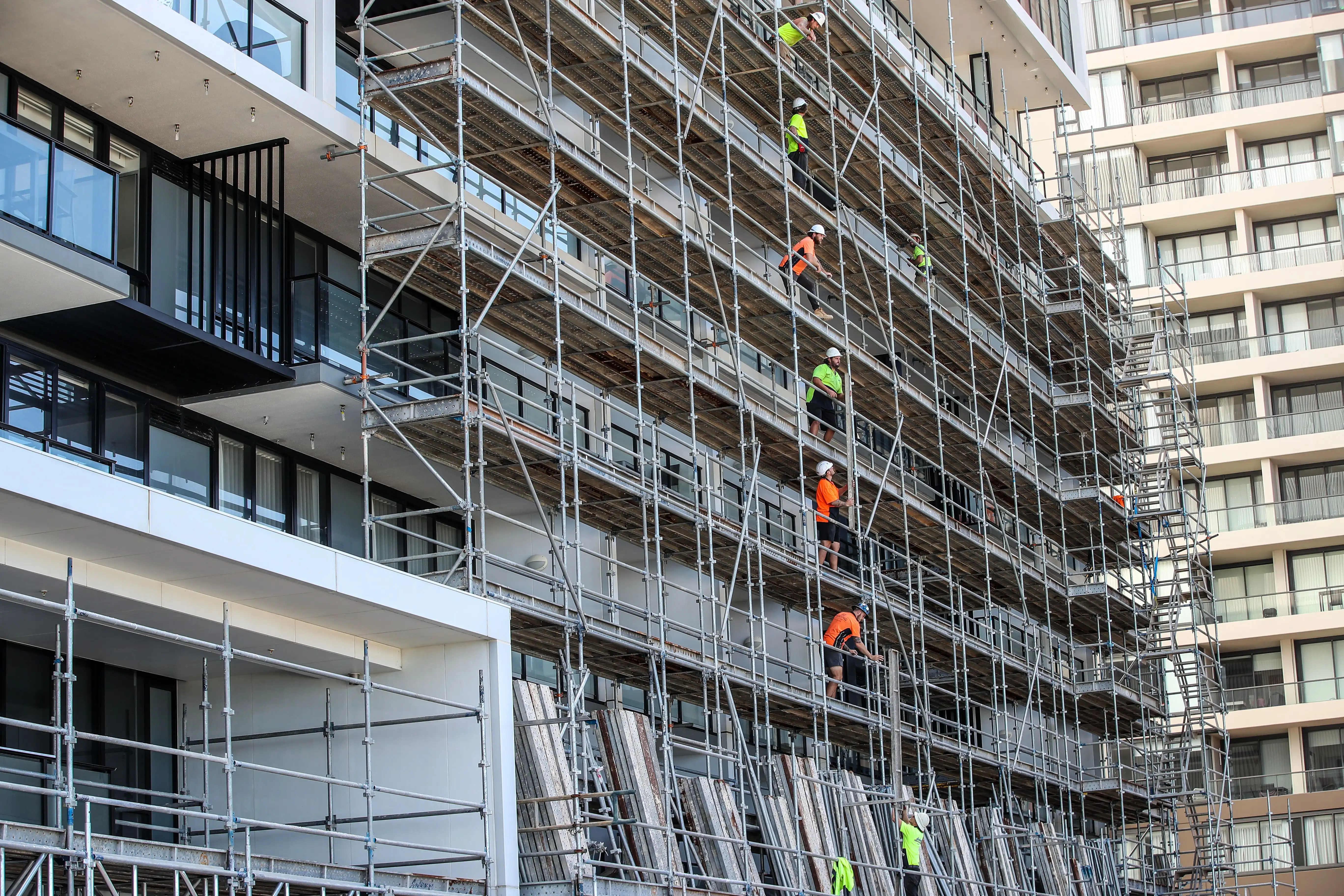 Workers install scaffolding at an apartment block