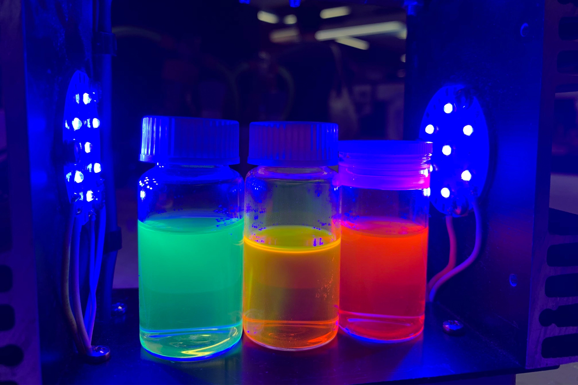Liquids in flasks glowing under fluorescent lights