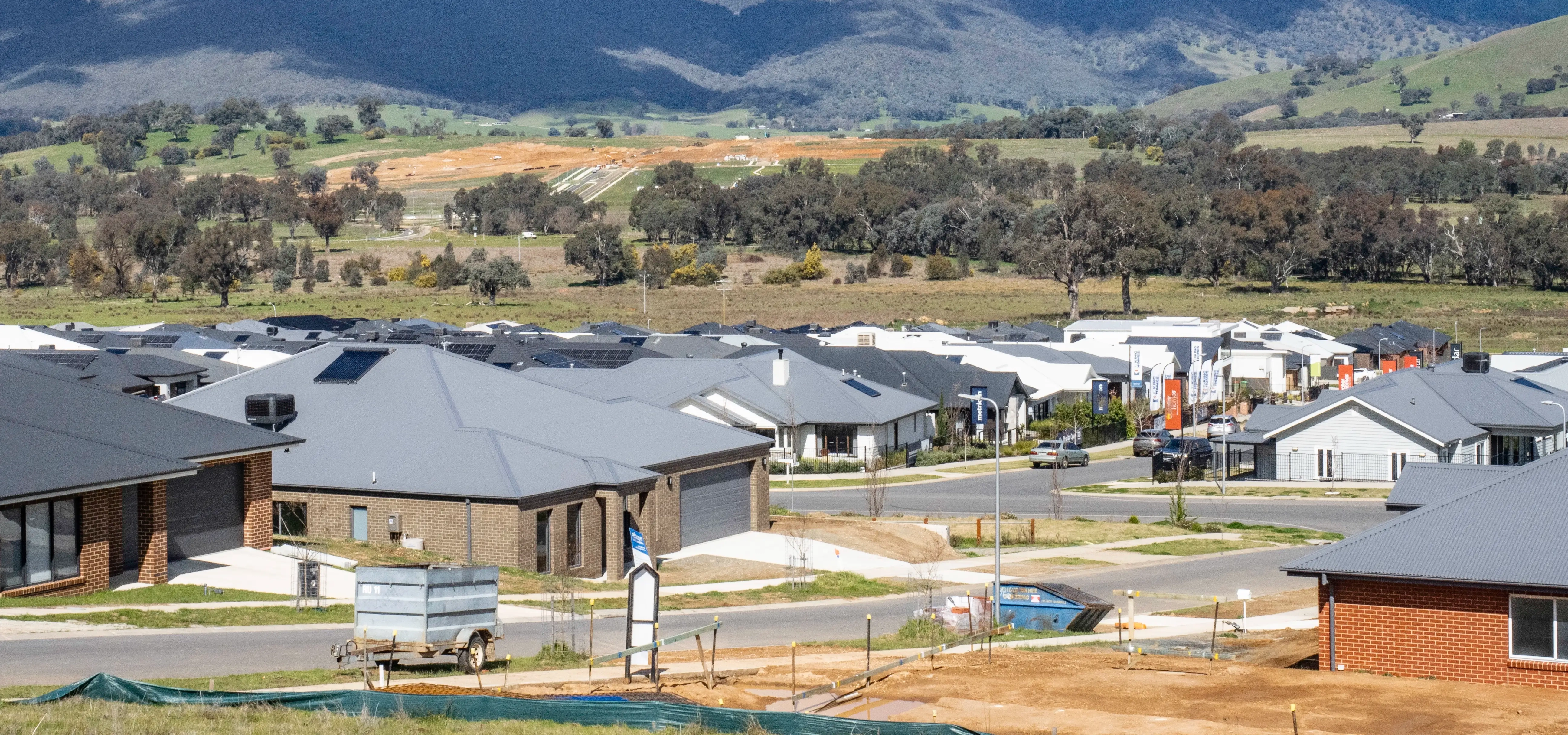 A new housing development in rural Victoria with many houses being built and rolling hills in the background