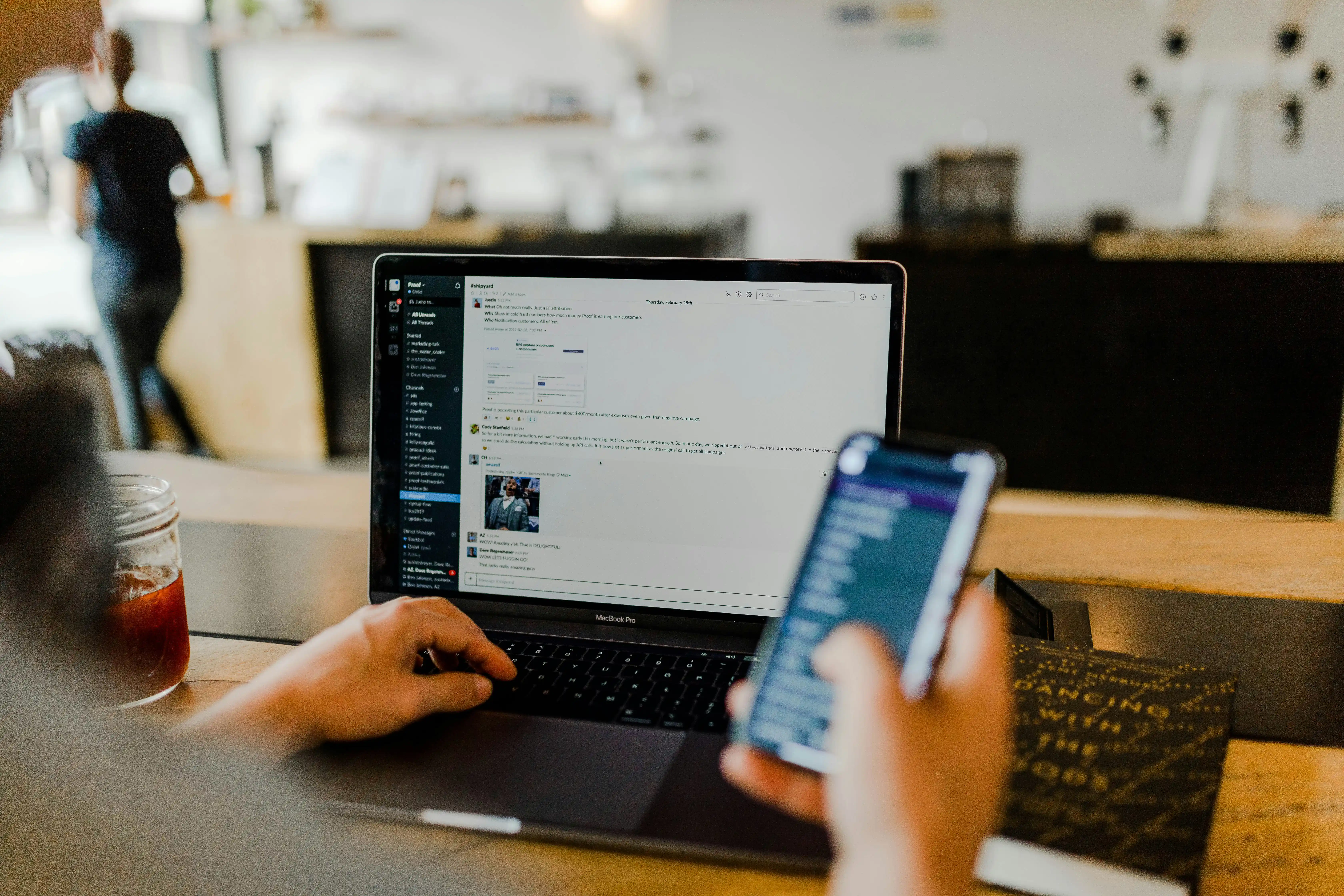 An office worker using a laptop and mobile phone together with an AI chat screen