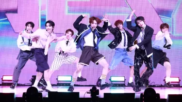 Seven member pop group dancing and singing on a stage