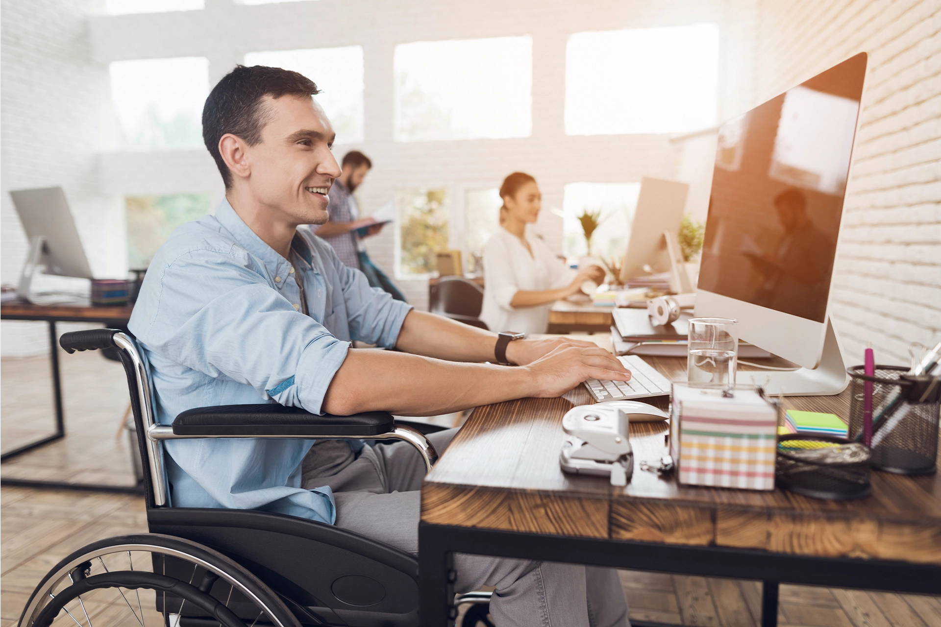 Smiling man in wheelchair sitting at an office desk
