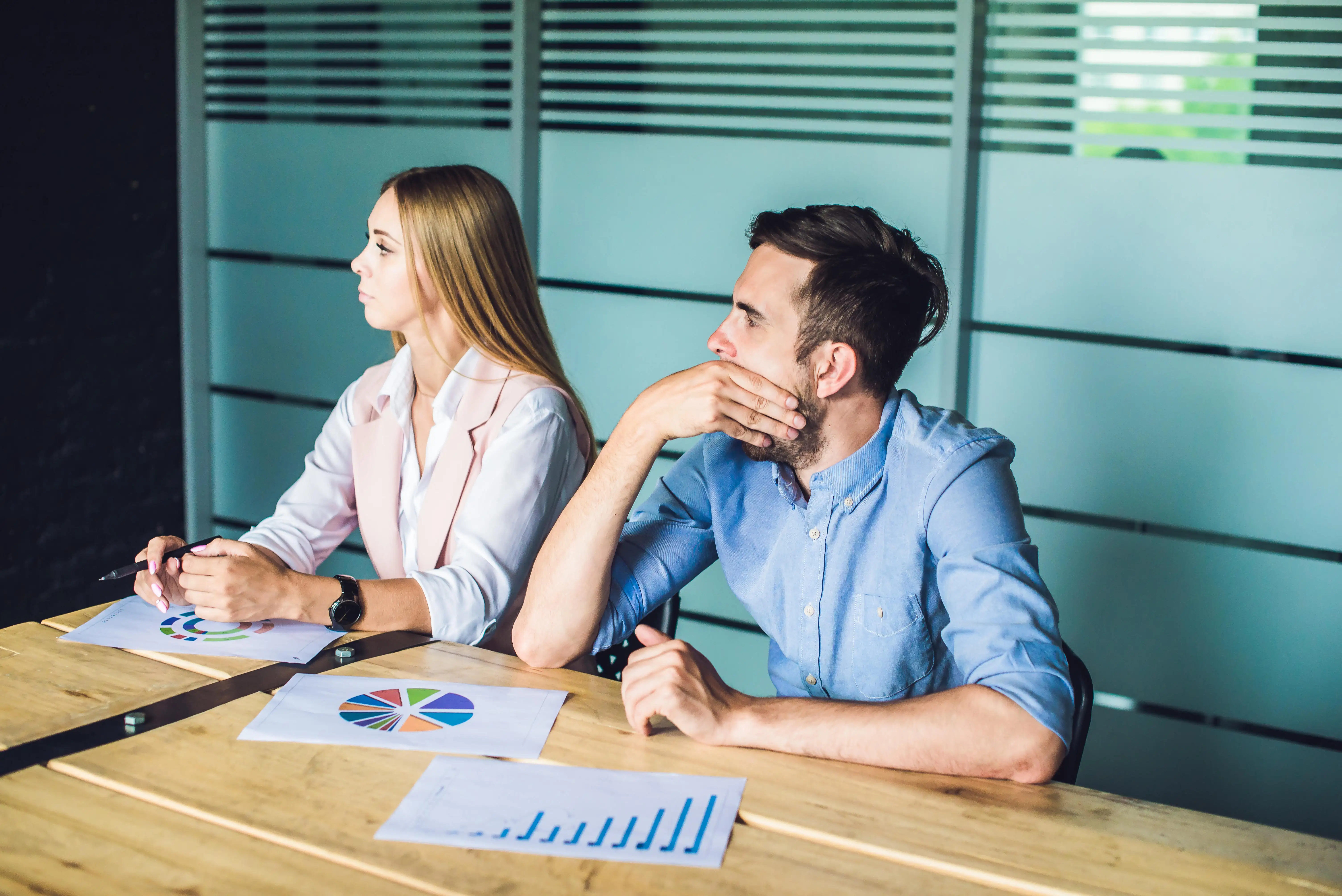 Two young business people bored in a meeting