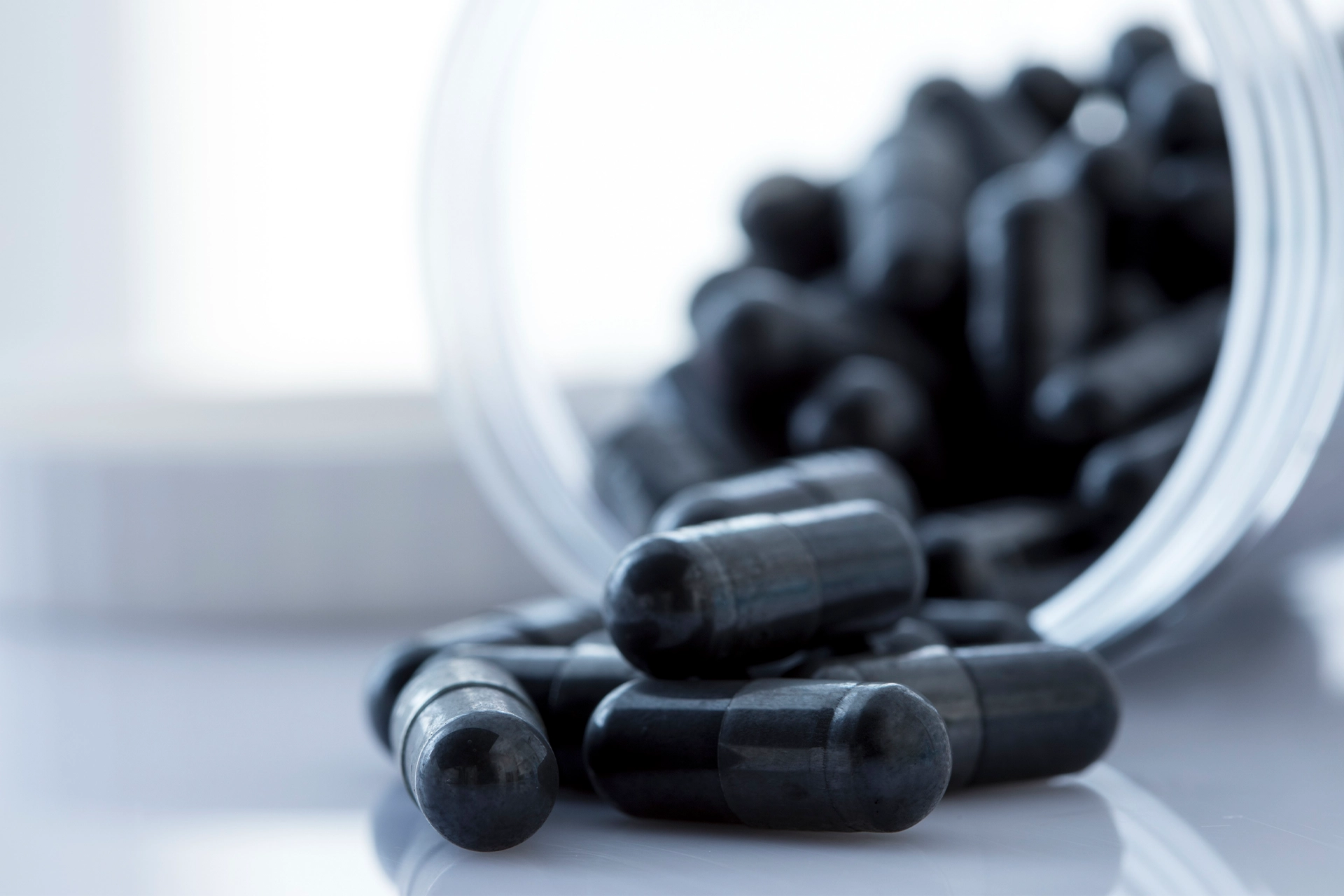 Black pills spilling out of a bottle