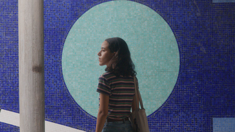 Young woman looking over her shoulder with mosaic wall in background