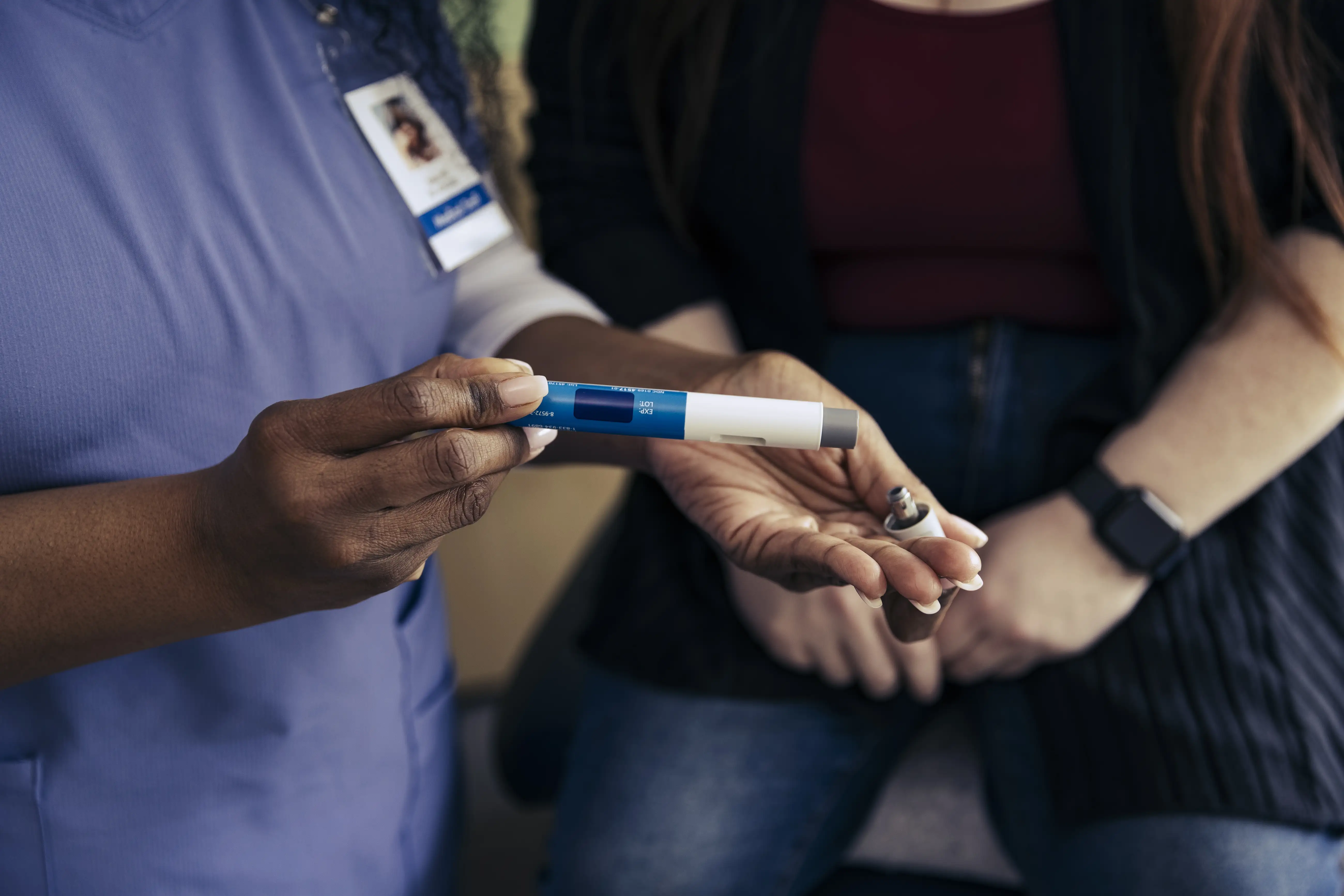 Hand of female nurse holding weight loss injection pen in exam room at doctor's office.