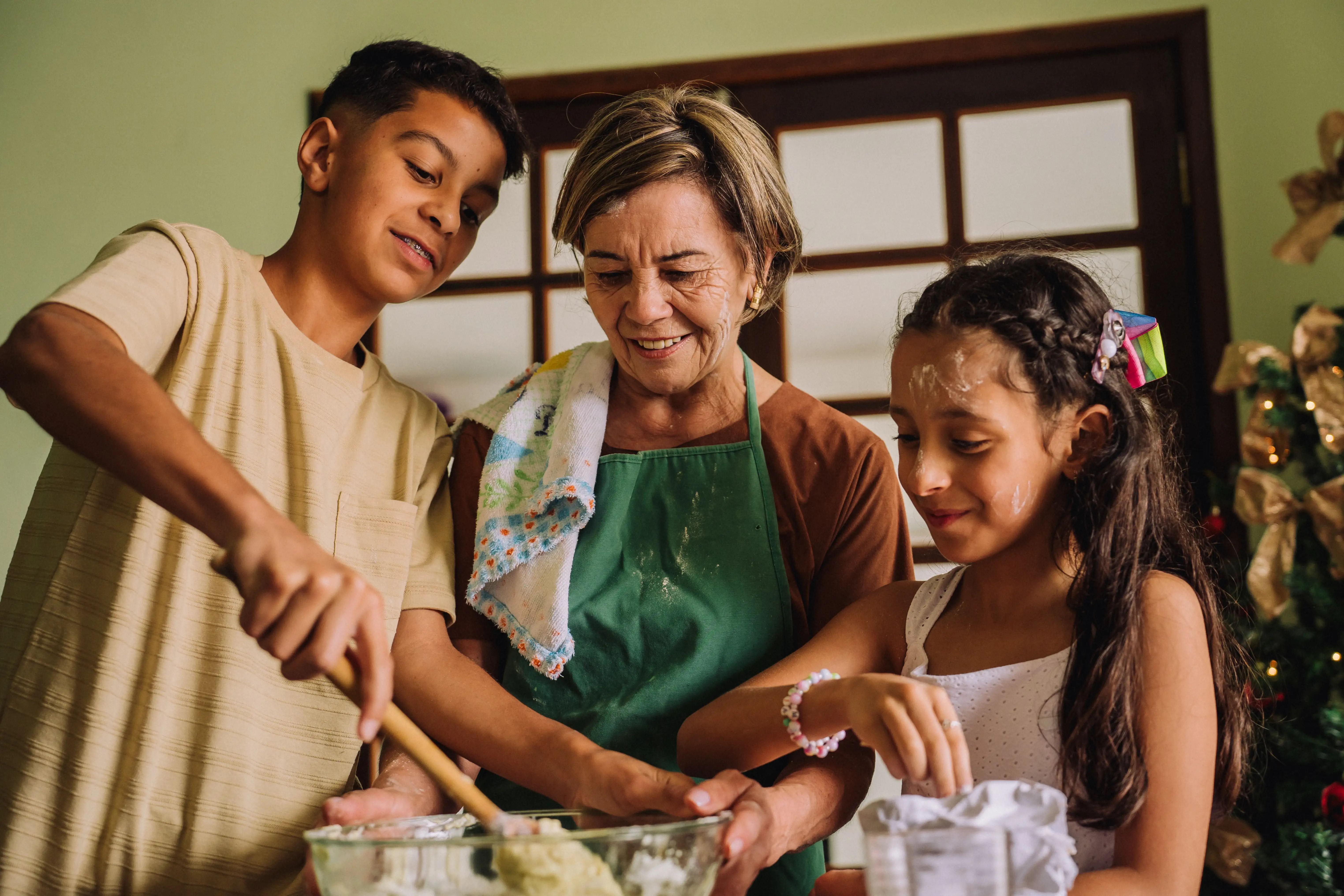 A grandmother helps her grandchildren stir a bowl to make a cake for Christmas
