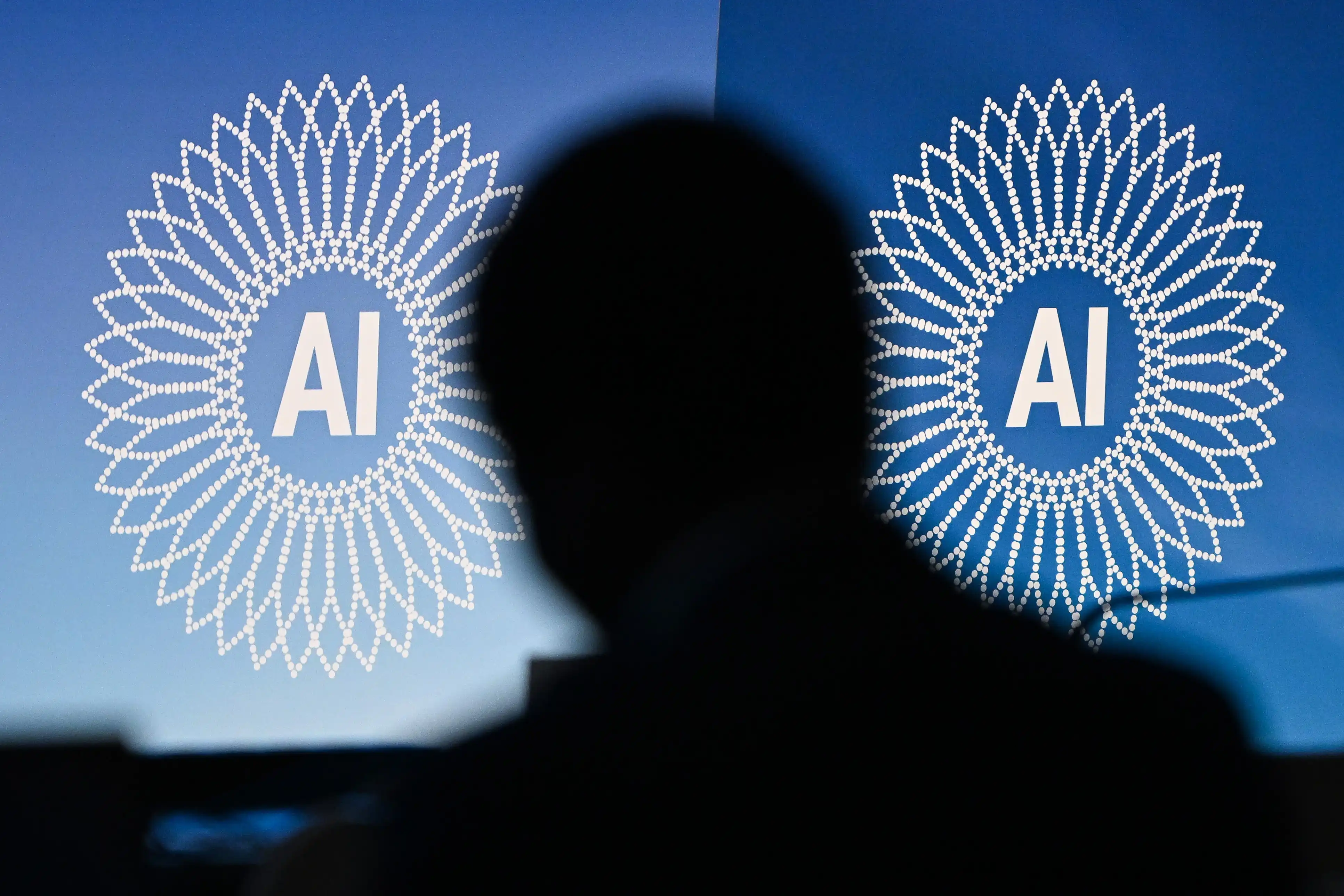 The silhouette of a man's head between two screens displaying AI symbols