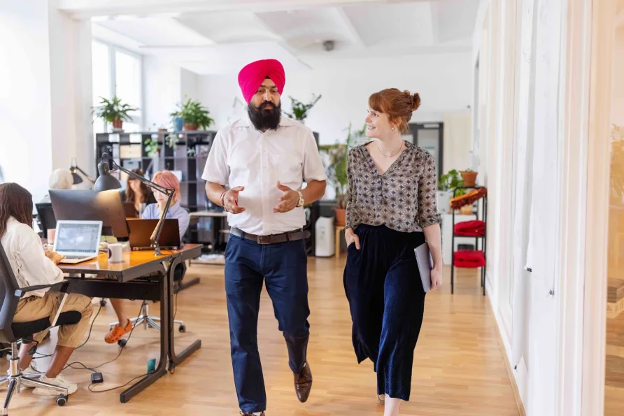 A man and a woman talking while walking through a modern looking office