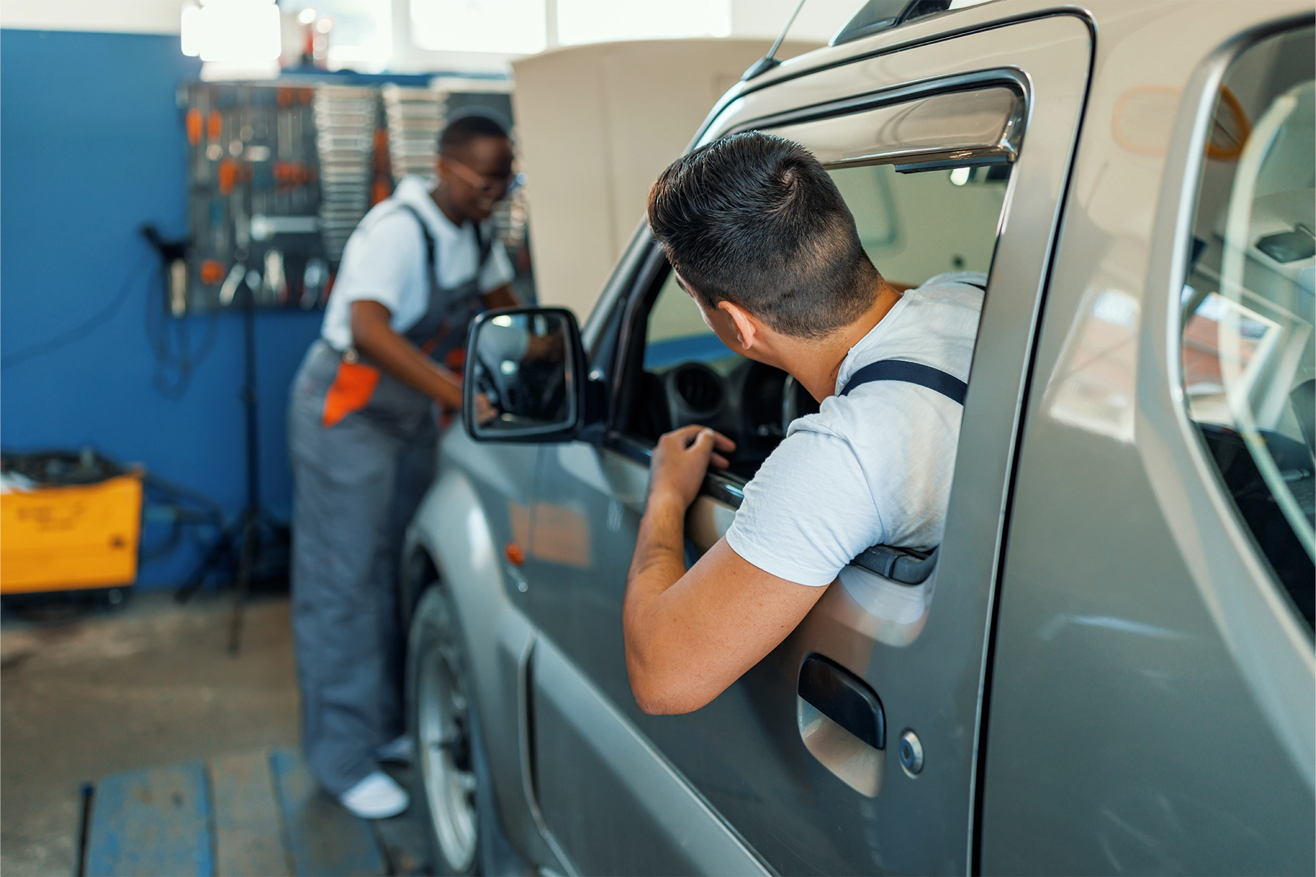 A man and a woman work on an SUV in a commercial garage