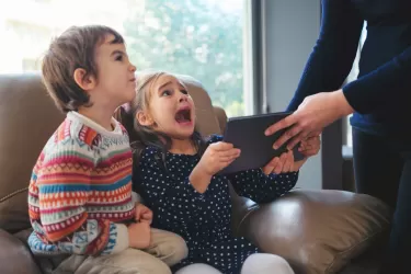 An adult takes a smart device from an angry child