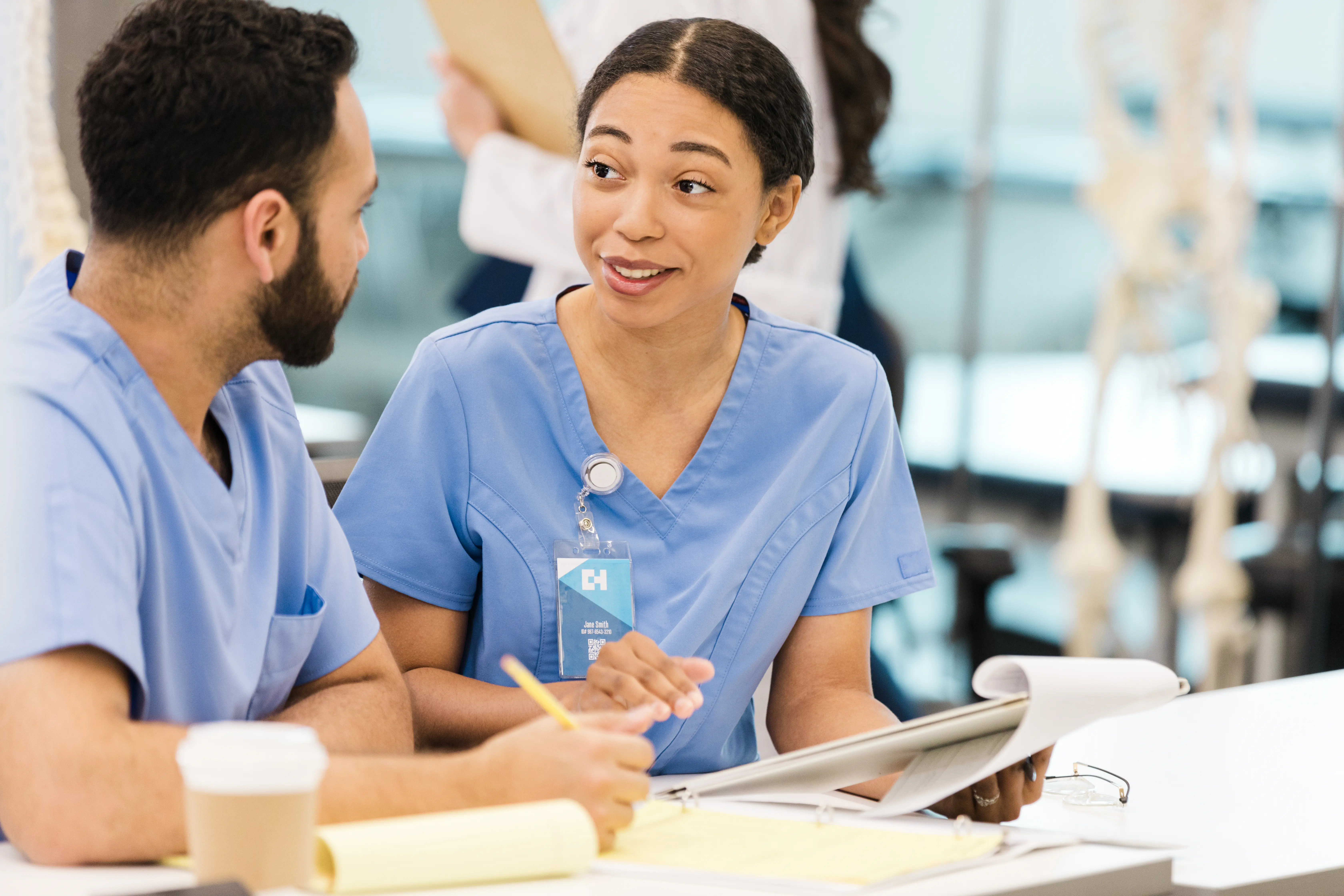 A young adult female medical student gestures as she explains the lecture to her classmate.