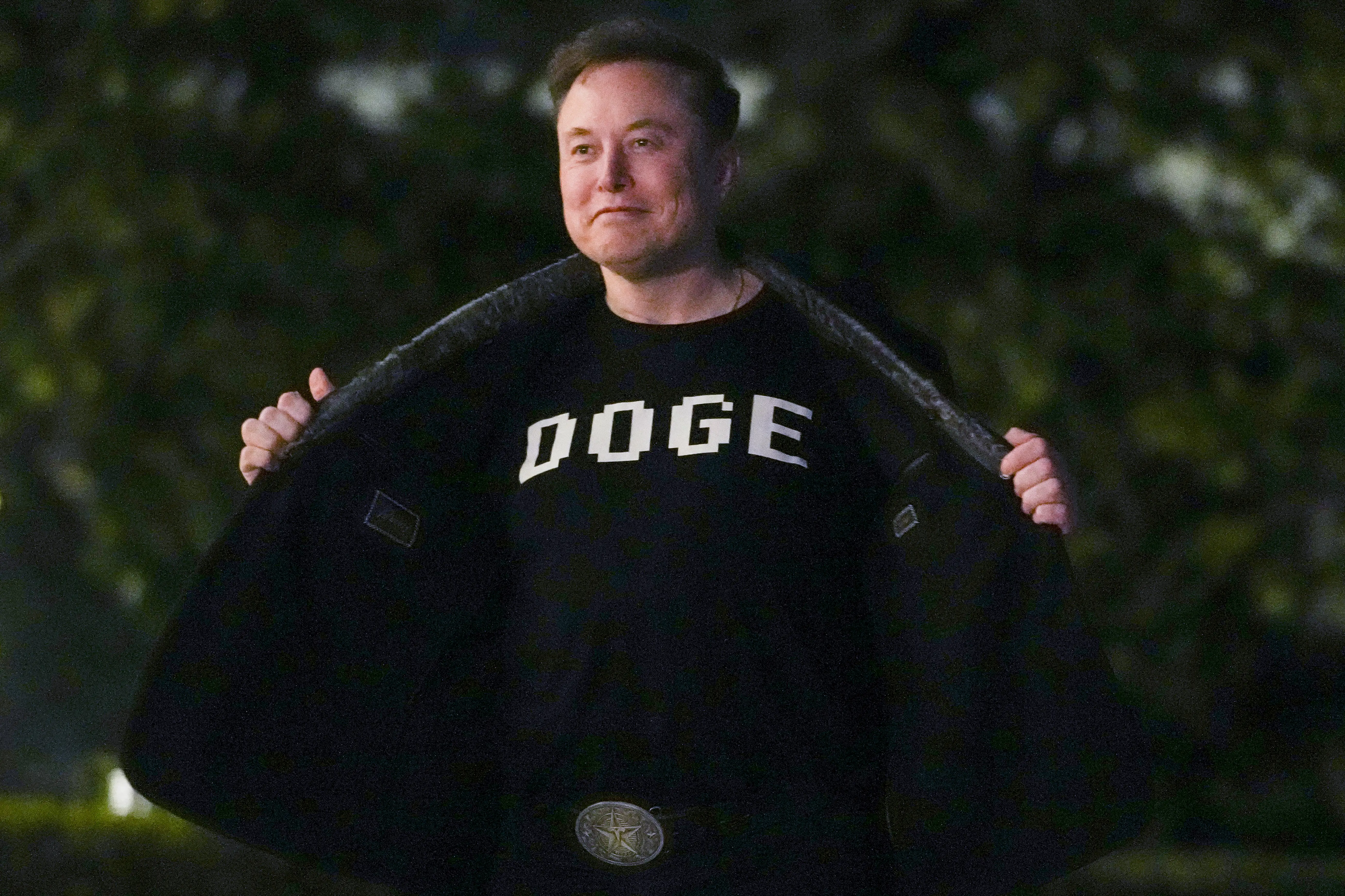 Elon Musk shows off a shirt that says "DOGE" as he walks on the South Lawn of the White House