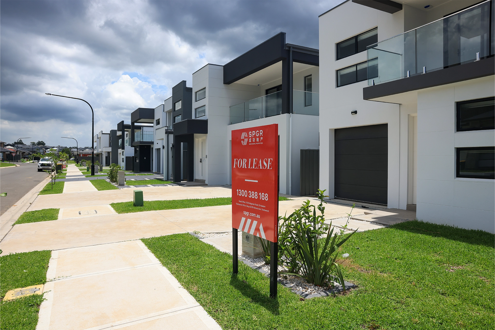 New houses on a street with a for lease sign outside the closest house