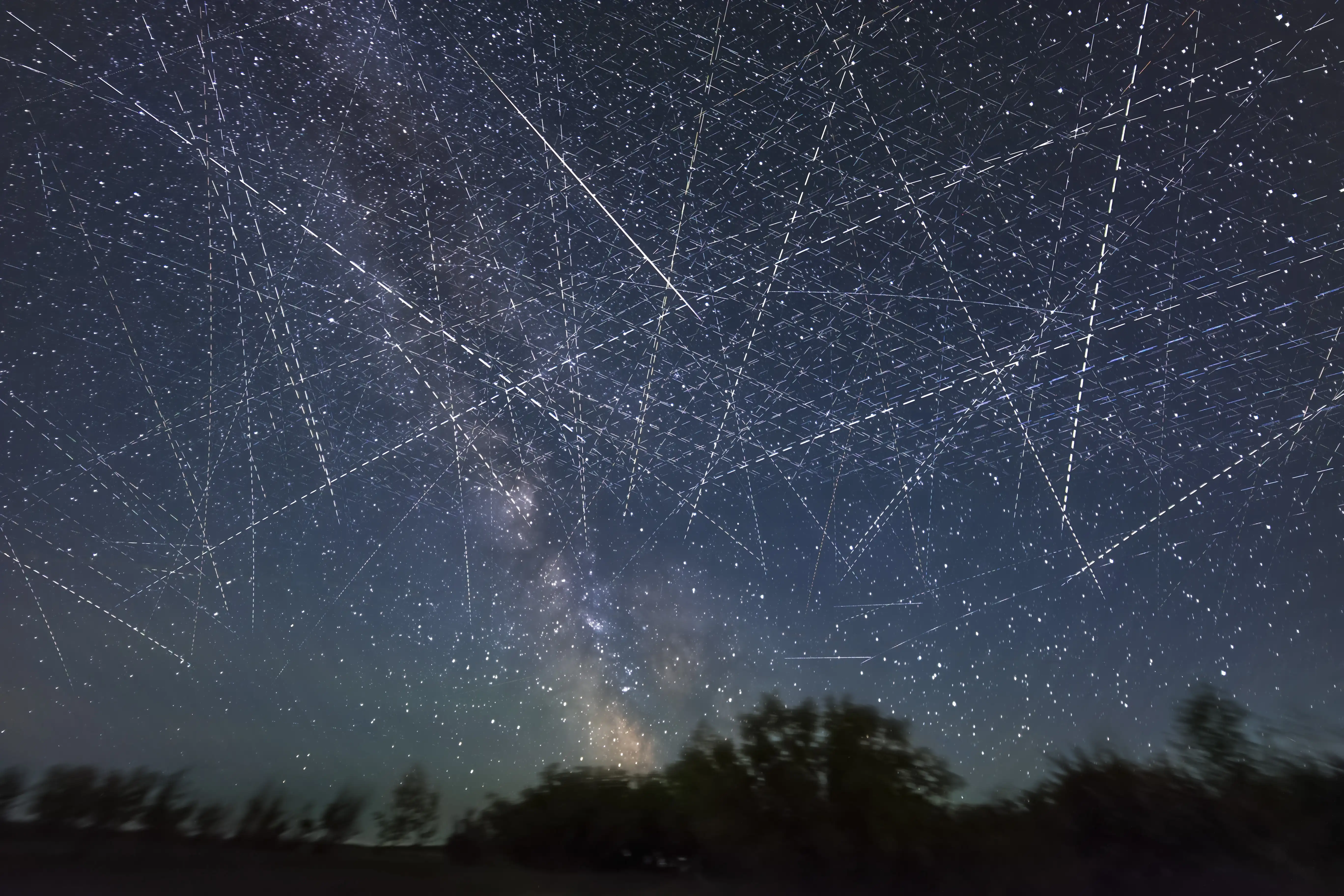 A long-exposure shot of a satellite-filled night sky creating lines across the stars