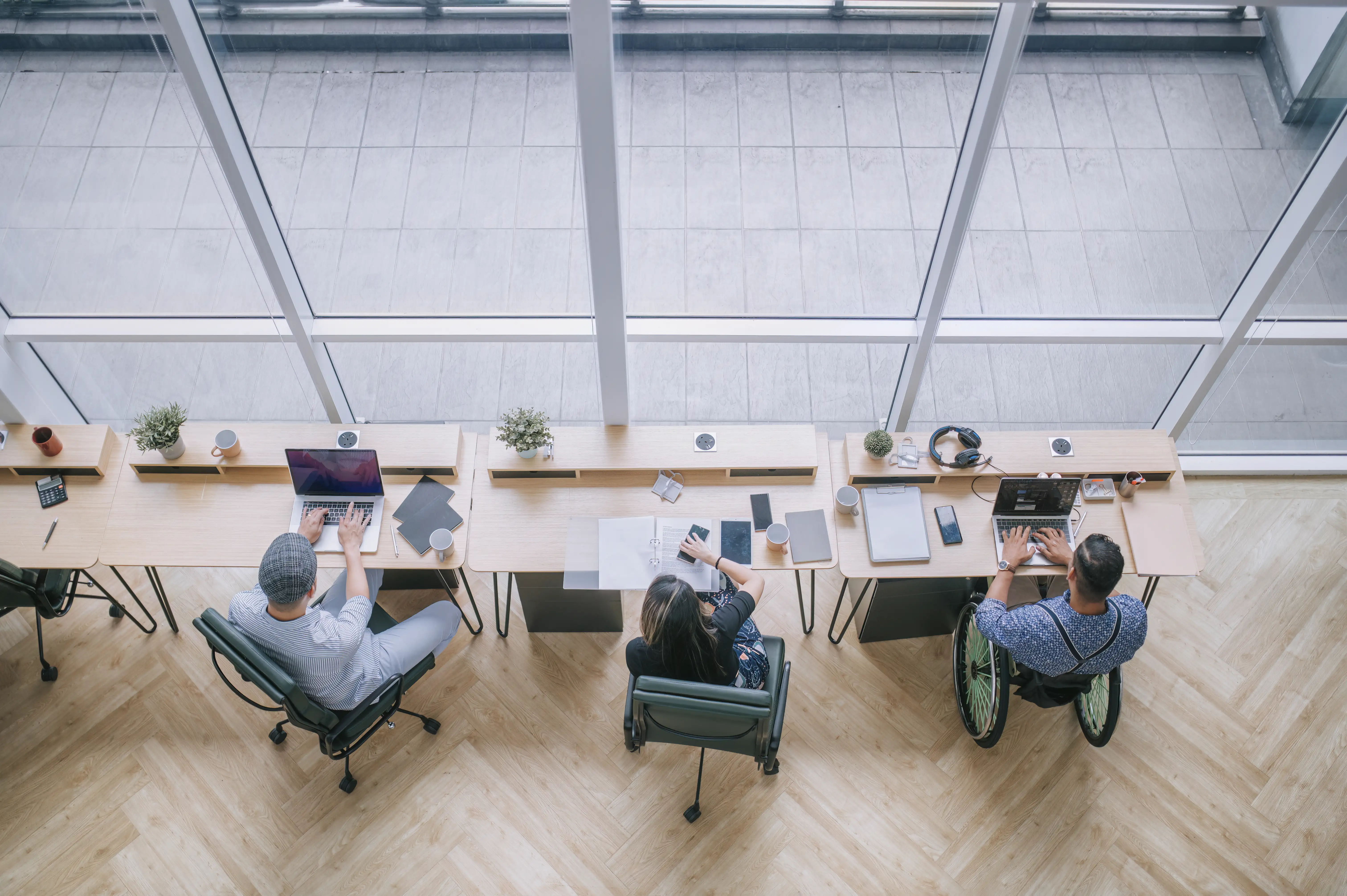 A diverse group of workers from different backgrounds and abilities working at an office workstation