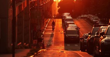A busy city street glowing red in sunset heat