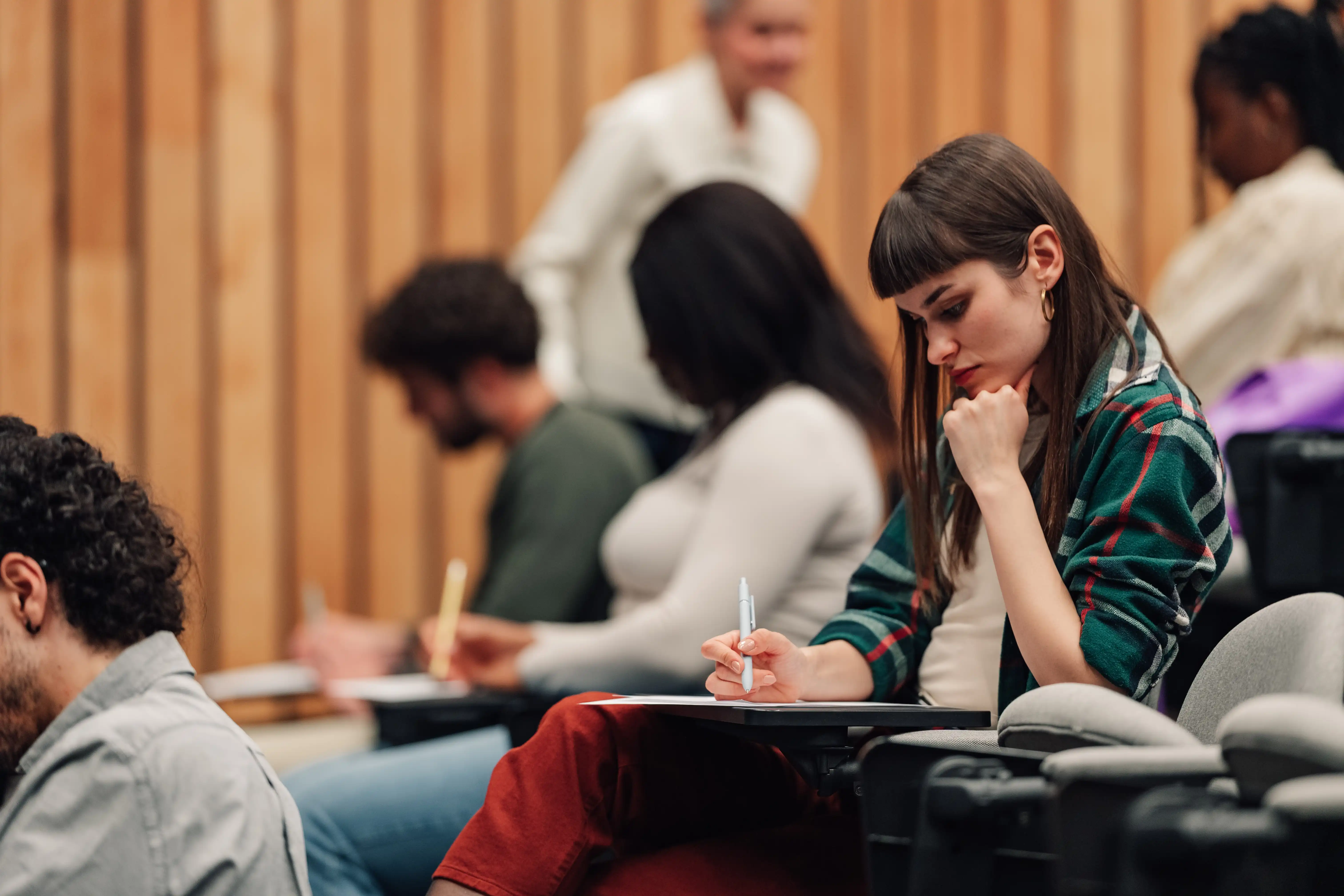 A female student writing notes in a lecture hall