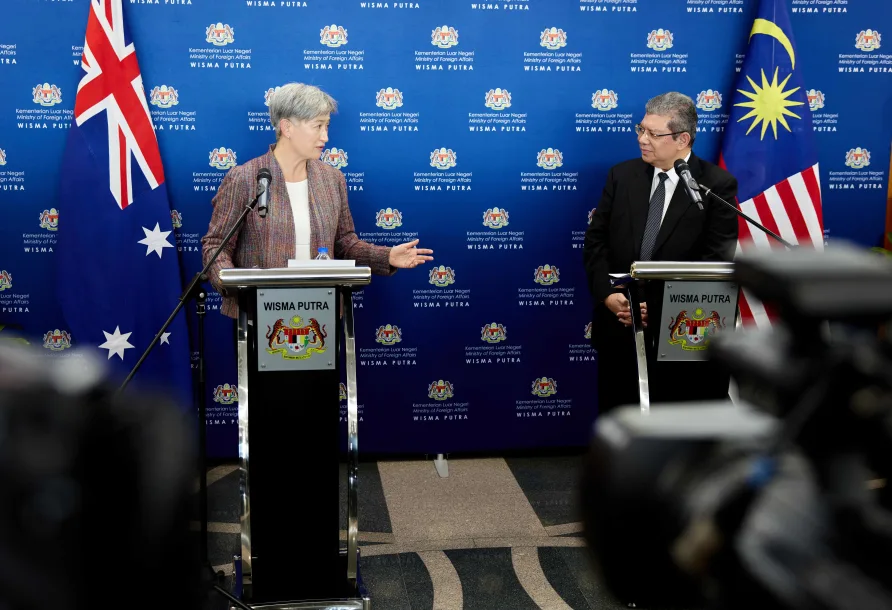 A woman and a man at separate lecterns at a press conference
