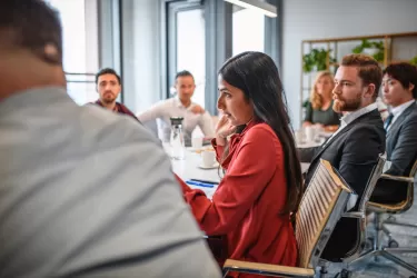 A woman and a group of men in an office meeting