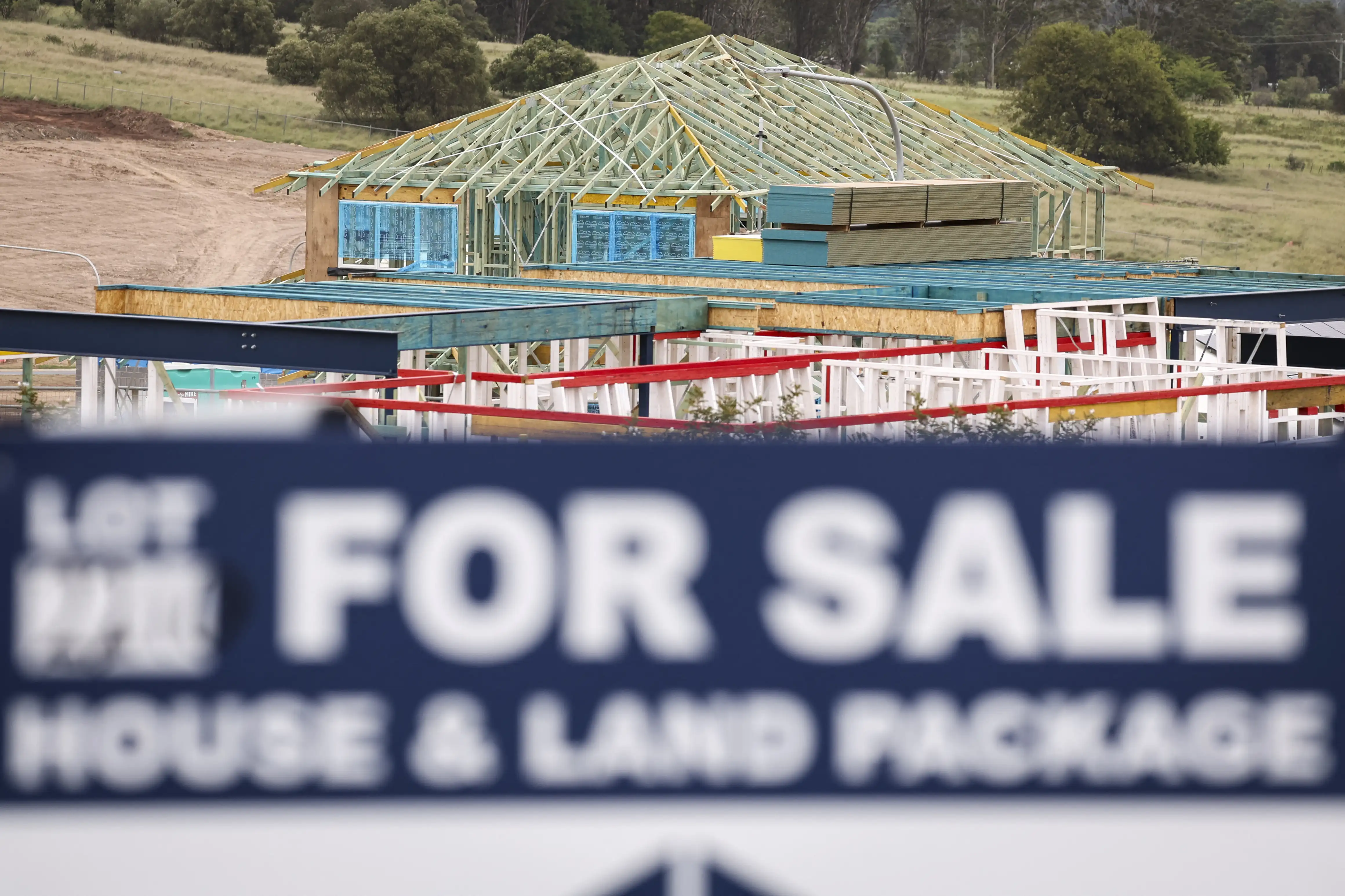 A sign is displayed on a vacant block in front of houses under construction at a housing development in Australia