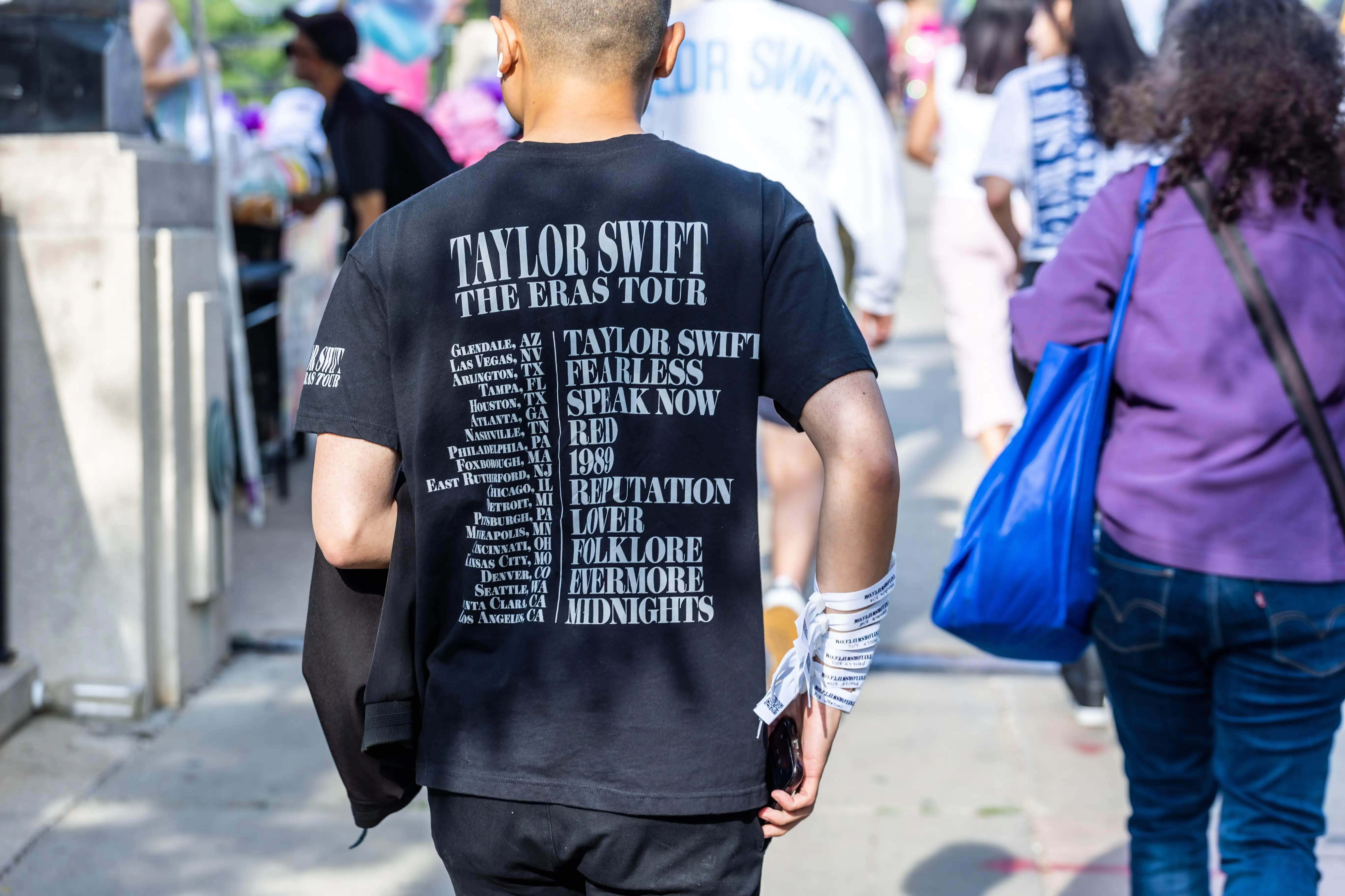 The back of a Taylor Swift fan heading to the concert wearing an Eras Tour t-shirt