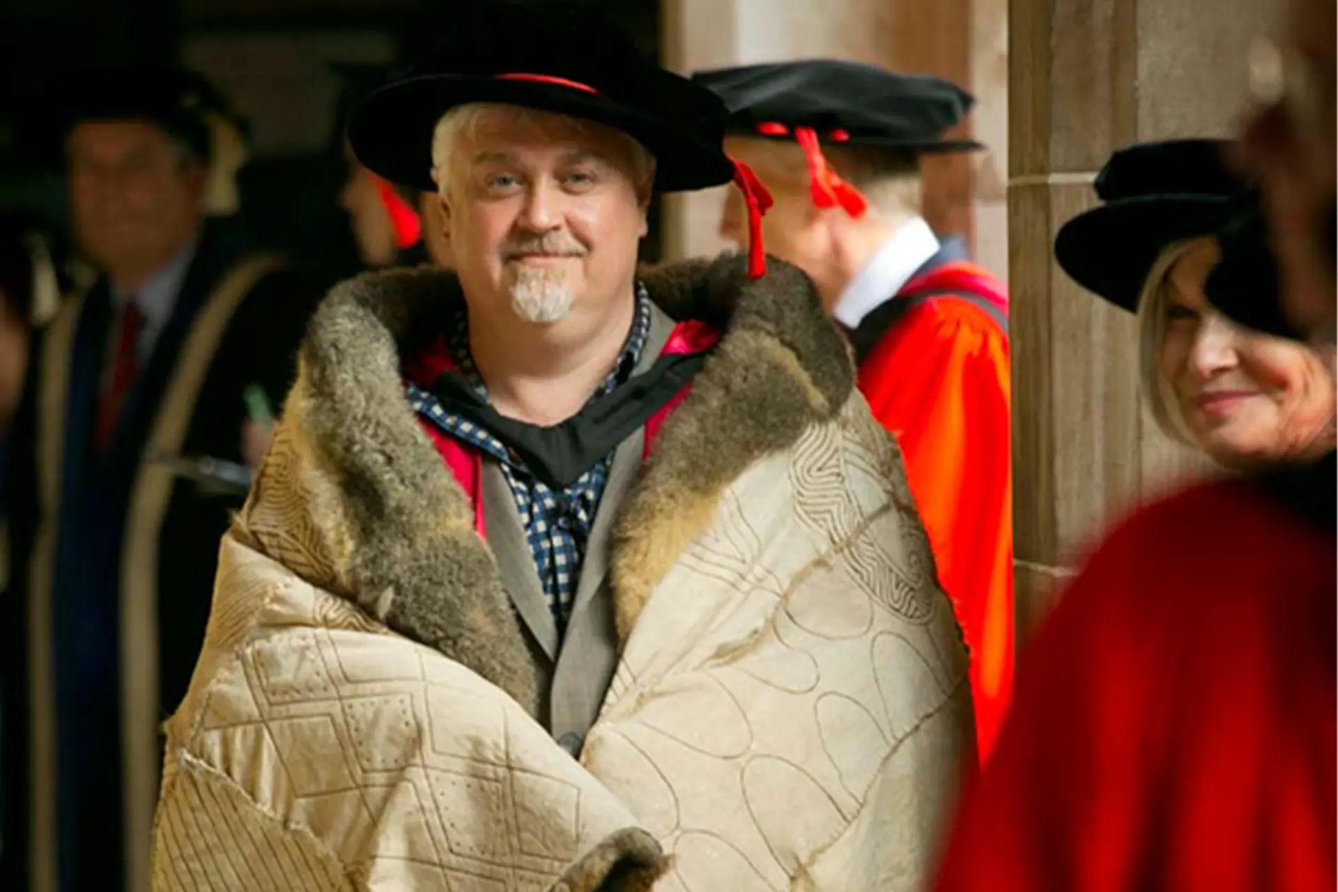 Ian Anderson dressed in academic regalia and a possum skin cloak at a graduation ceremony