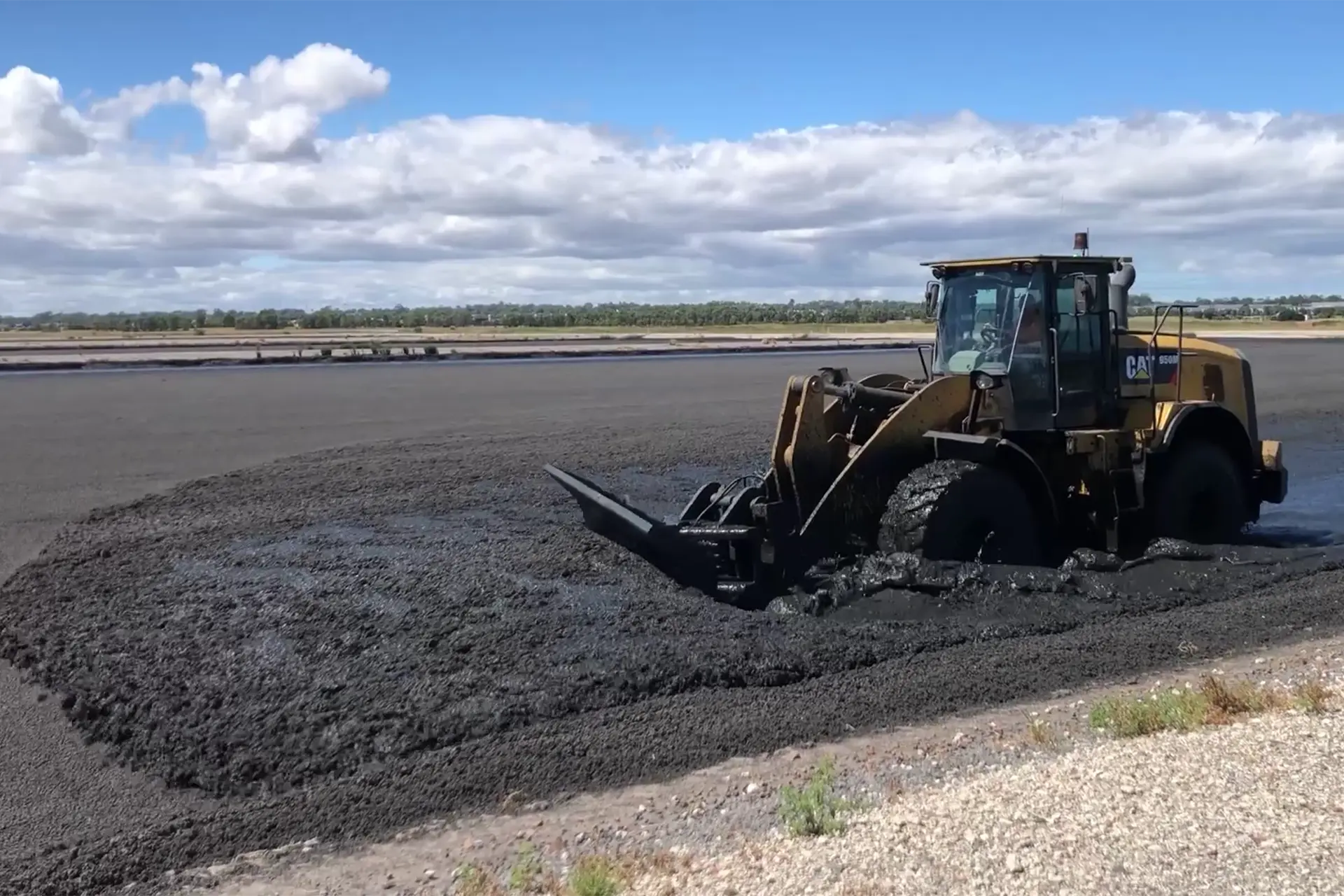 A tractor mixing sludge in a large open pool