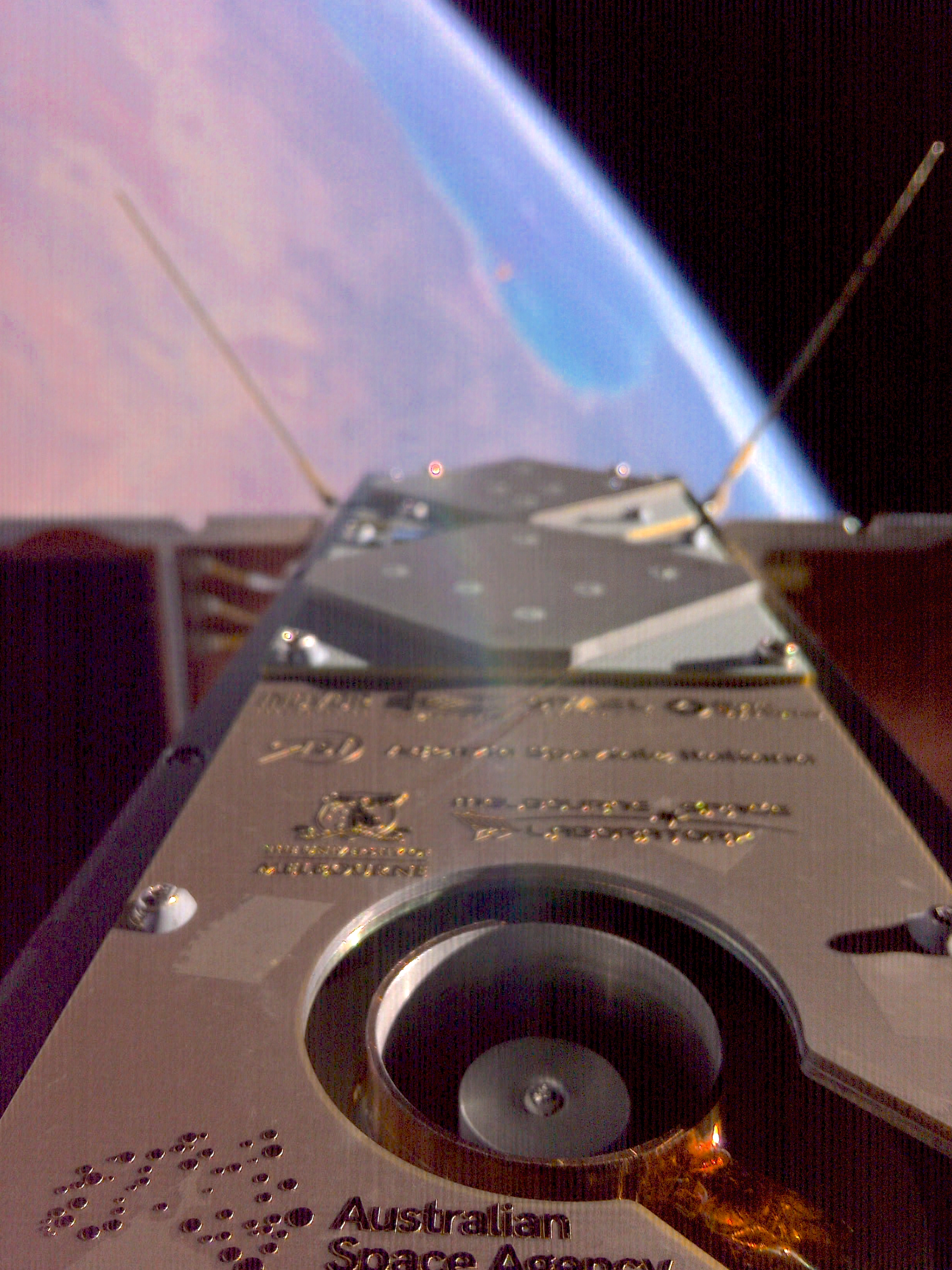 A degraded image of the underside of a small orbiting satellite looking towards Earth