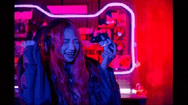 A young woman gamer celebrating a win with a console in her hand.