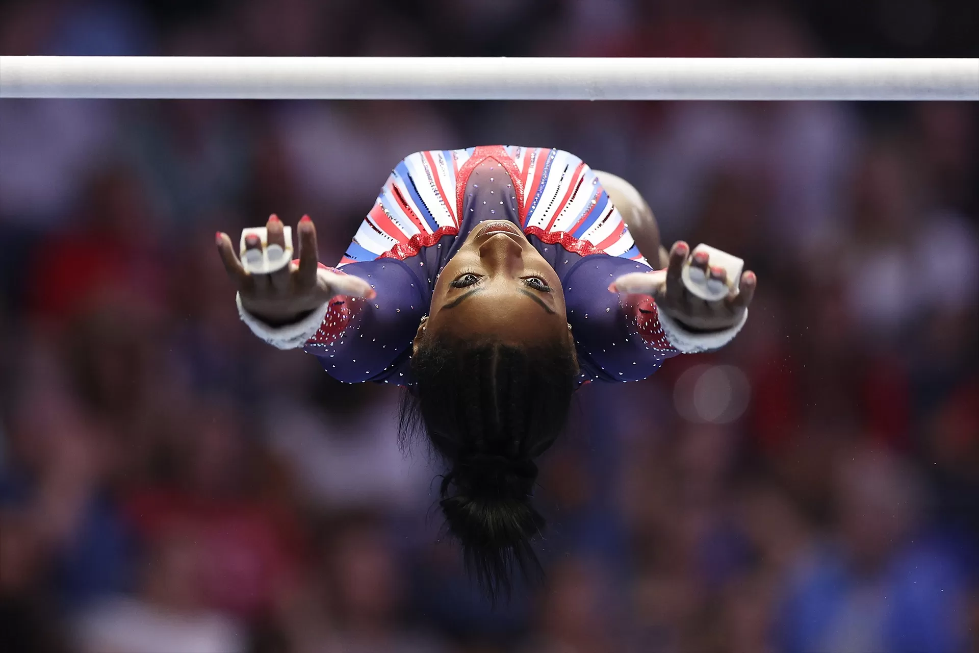 Simone Biles suspended in the air during a parallel bars routine