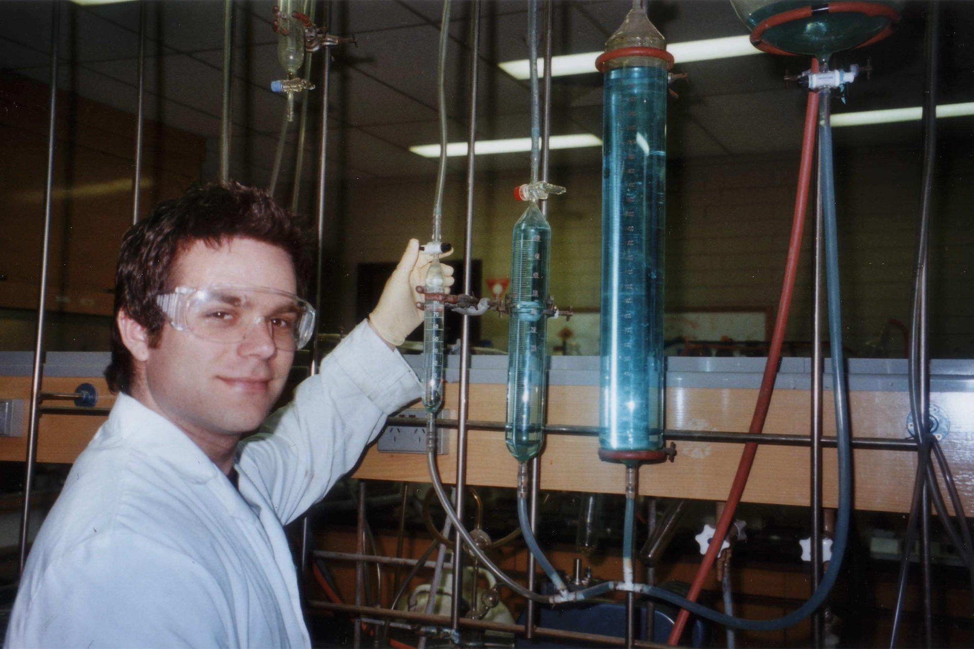 A young Tash Polyzos running an experiment in an old-looking chemistry laboratory