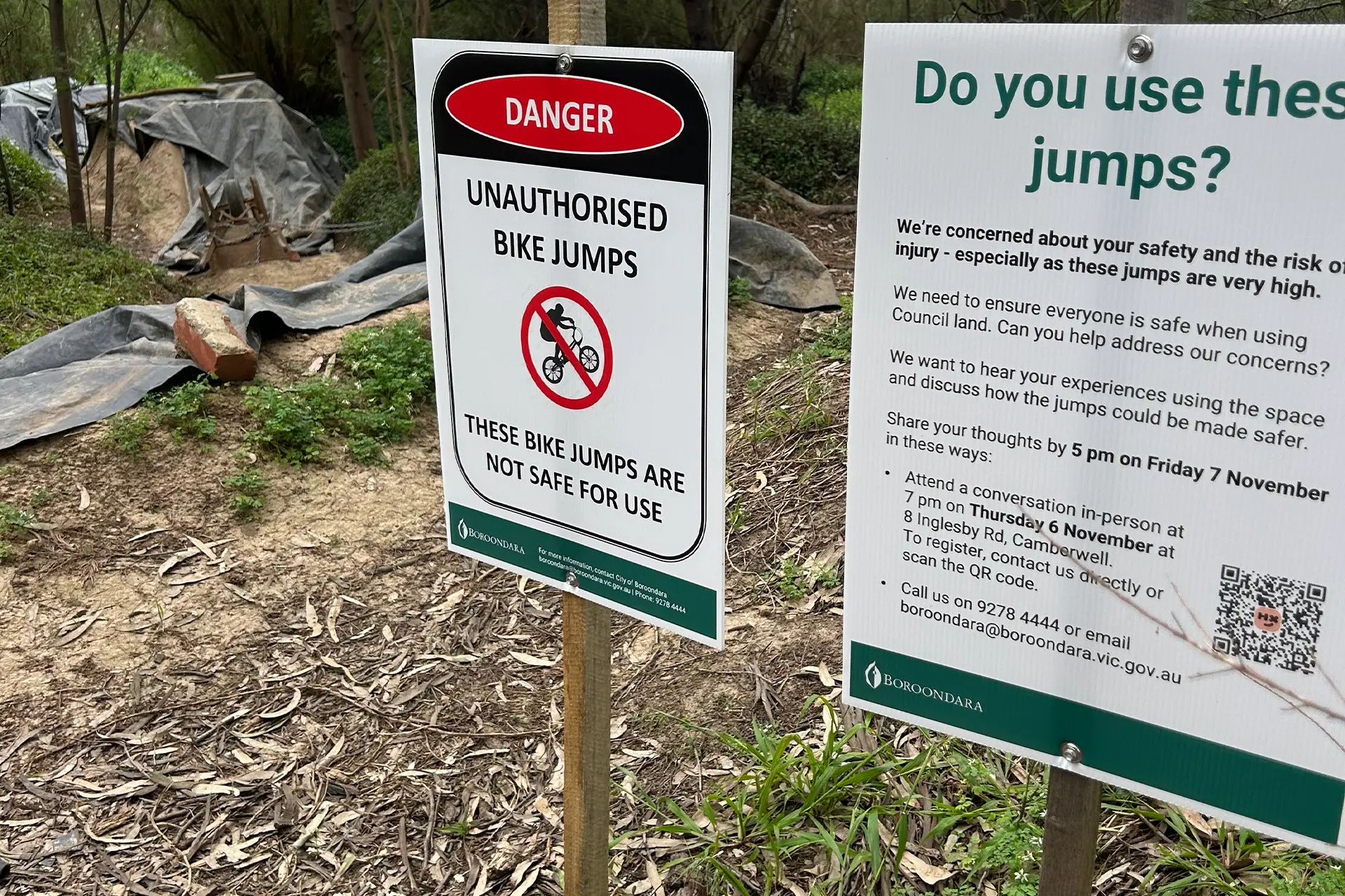 Two signs next to a dirt BMX track, one saying no riding, and one asking for feedback on the jumps to council