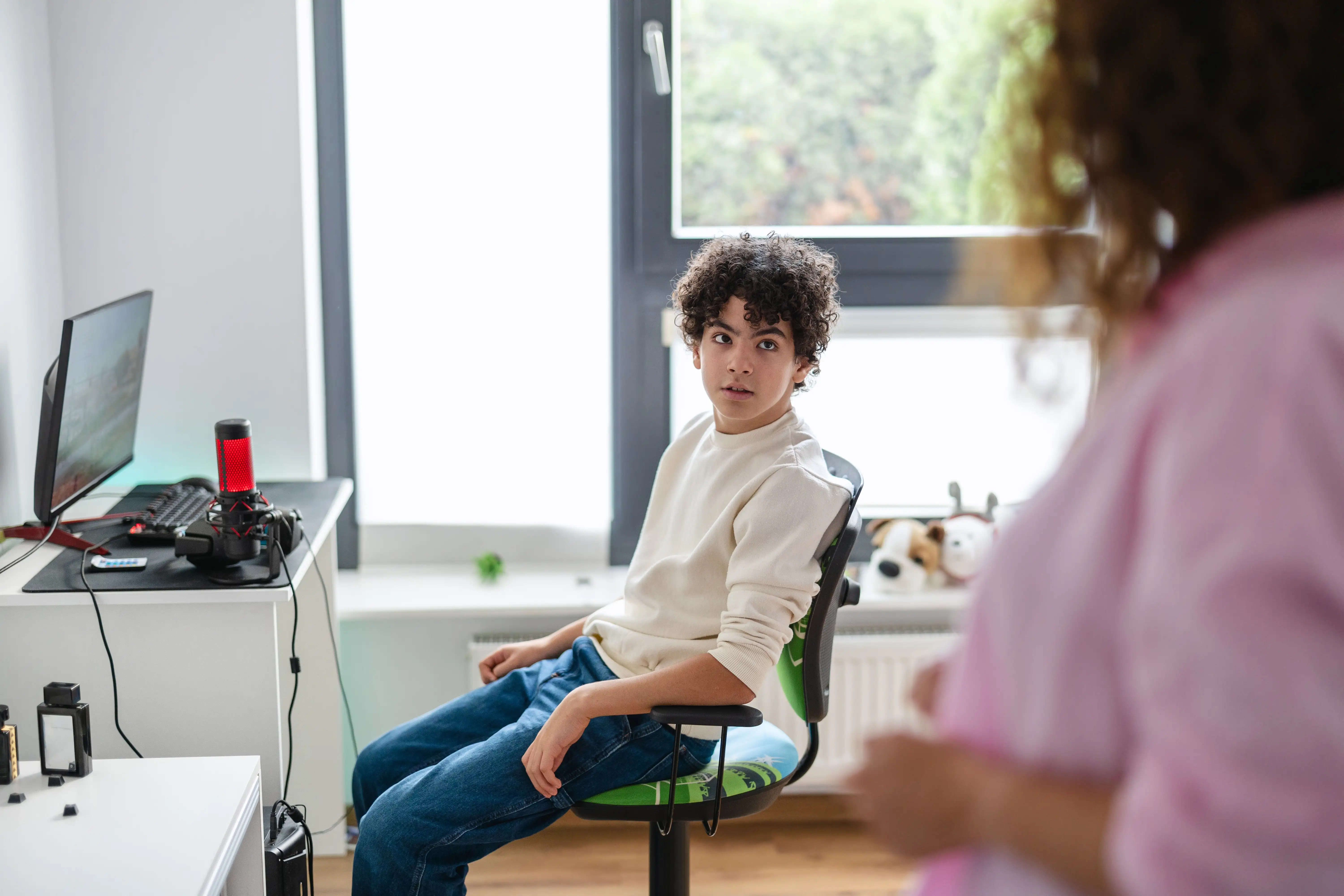 A teenage boy looking angry at his parent while sitting in front of his gaming console