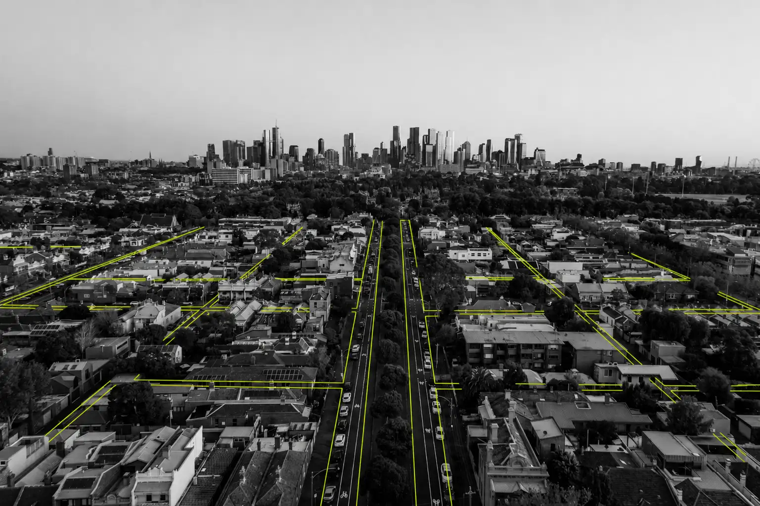 A black-and-white photo of tram tracks leading toward Melbourne's CBD with elements picked out in lime green