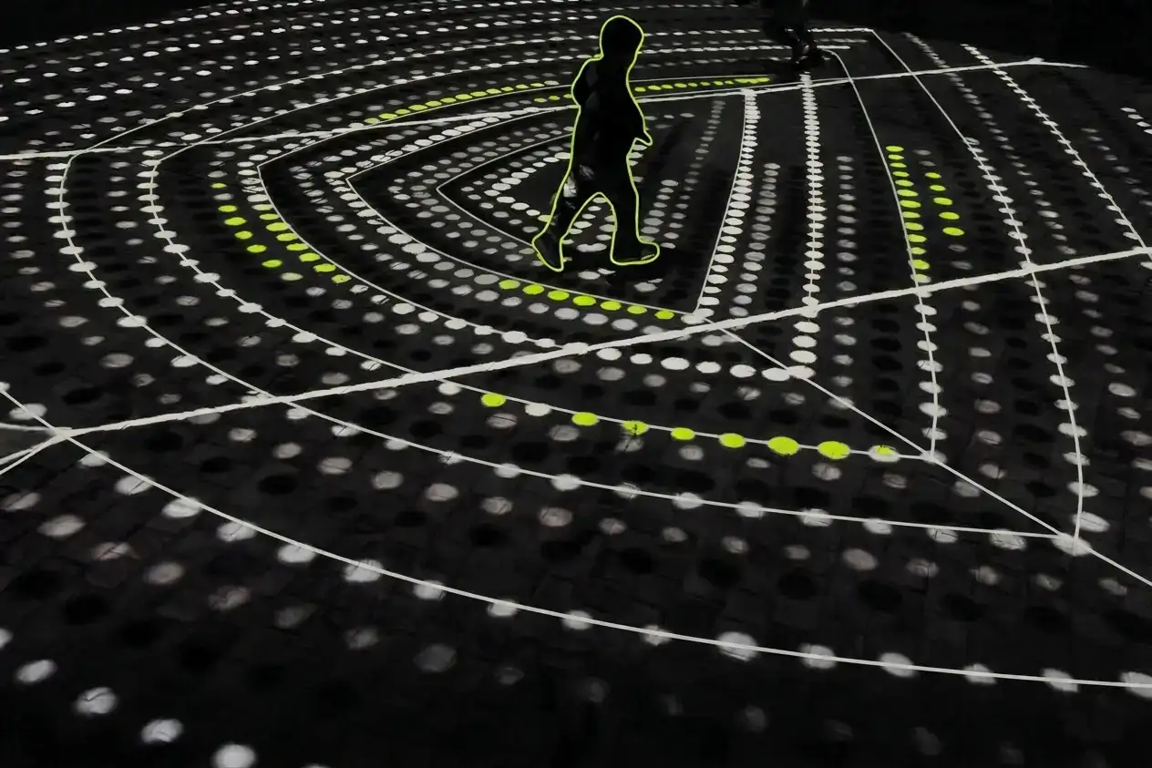 A black-and-white photo of a small child running through a projection of Indigenous art wit elements picked out in lime green