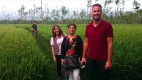 Group of people standing in a rice field.