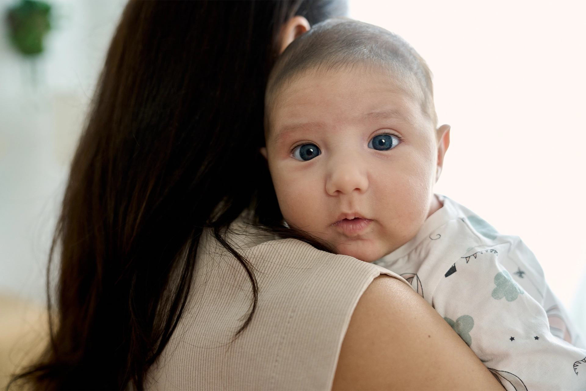 Mother facing away holding a baby staring at the camera