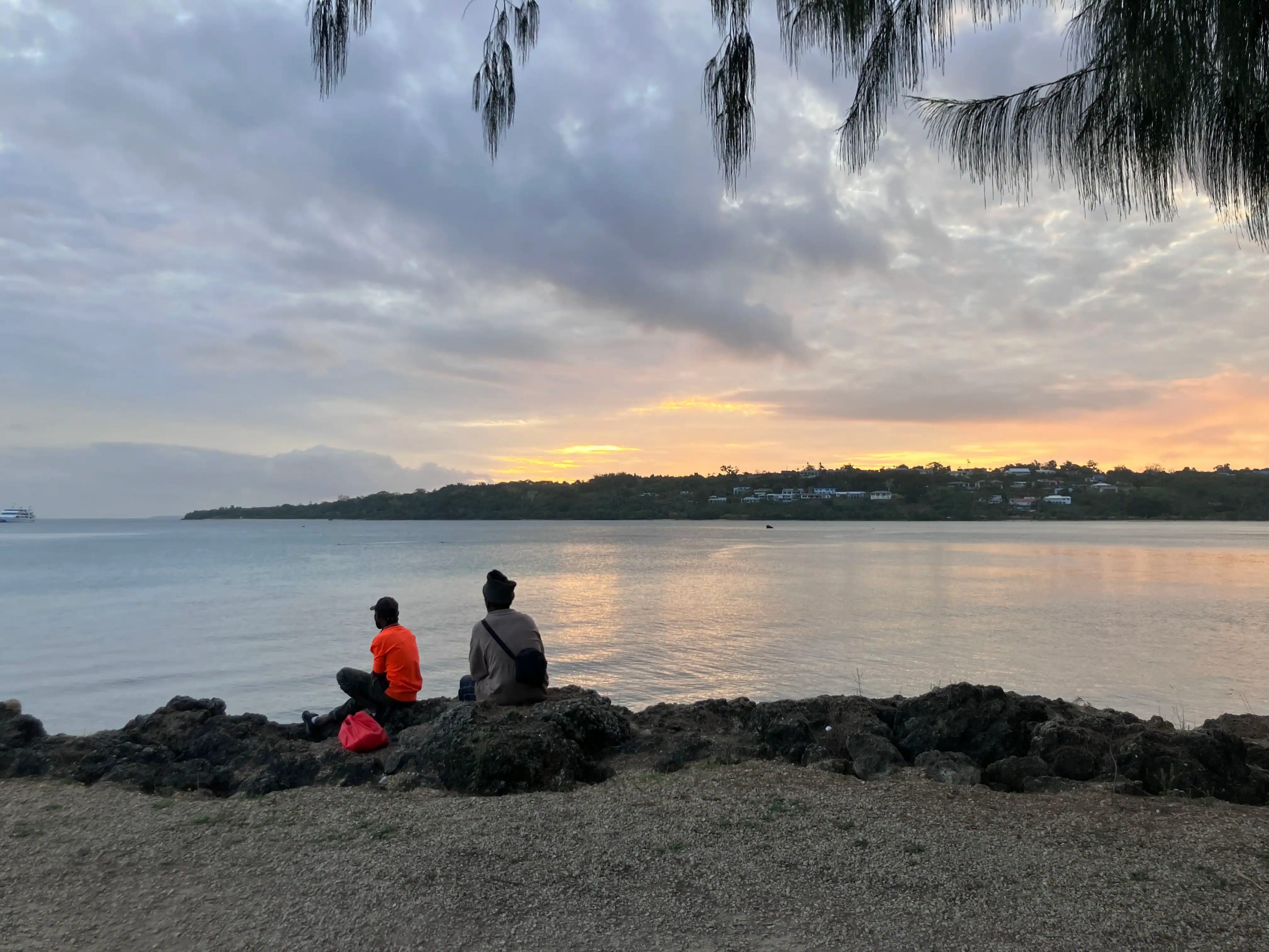 Two people sit on edge of water in Vanuatu