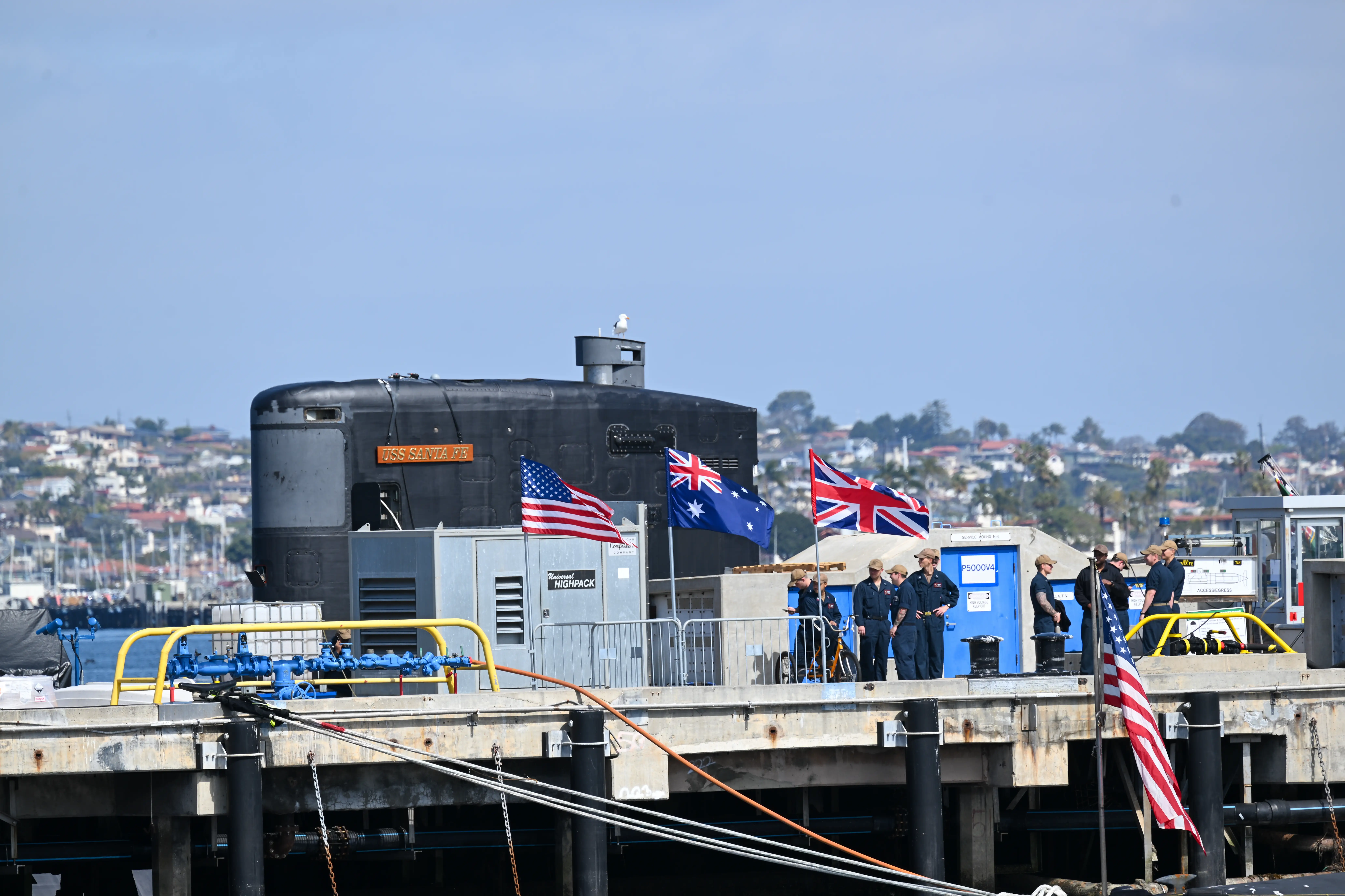 A submarine in the background of an AUKUS meeting between Australia, the UK and the US 
