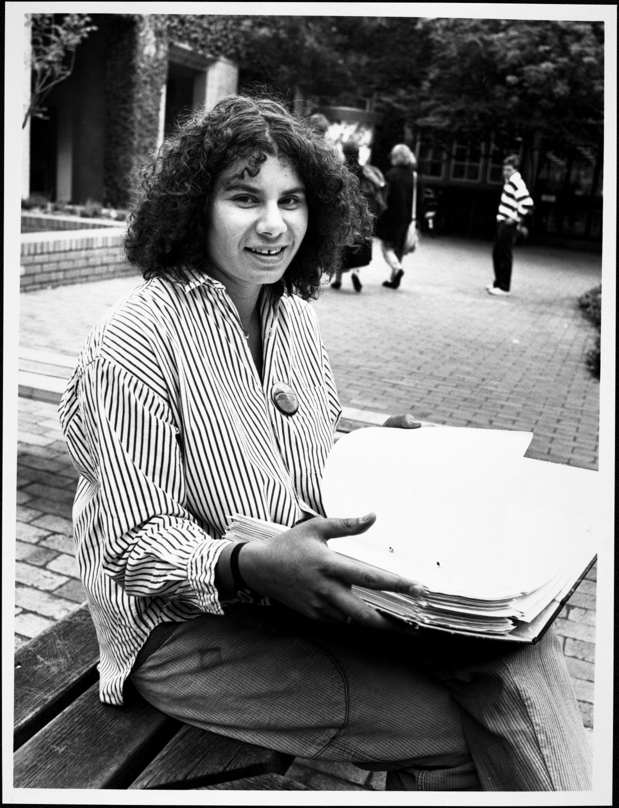 A woman sitting on a bench with a stack of papers