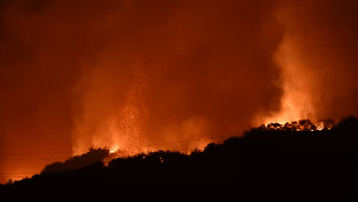 A firefighting helicopter drops water on a huge wildfire in Los Angeles