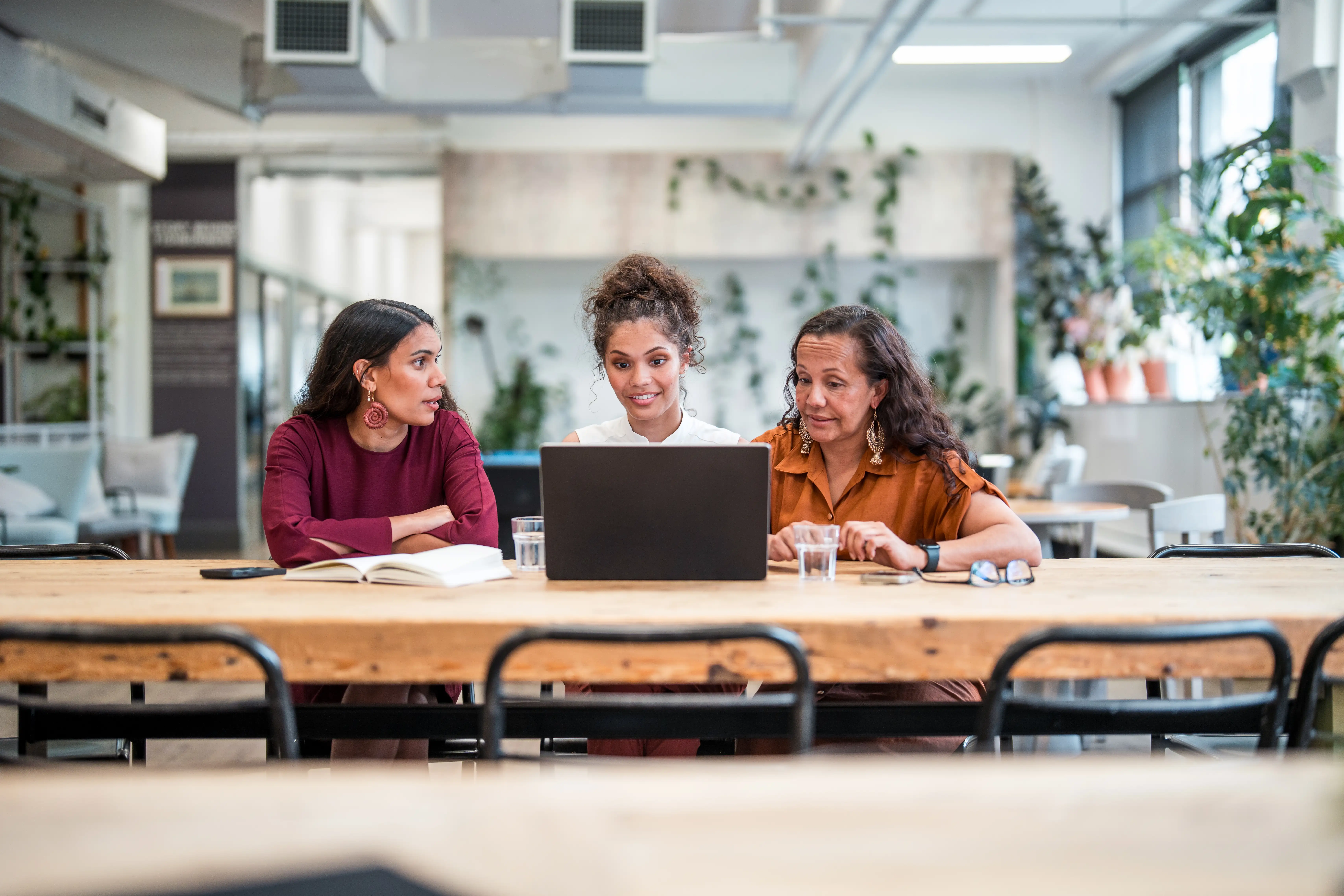 Young adult and mature Aboriginal businesswomen collaborate in a modern office