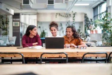 Young adult and mature Aboriginal businesswomen collaborate in a modern office