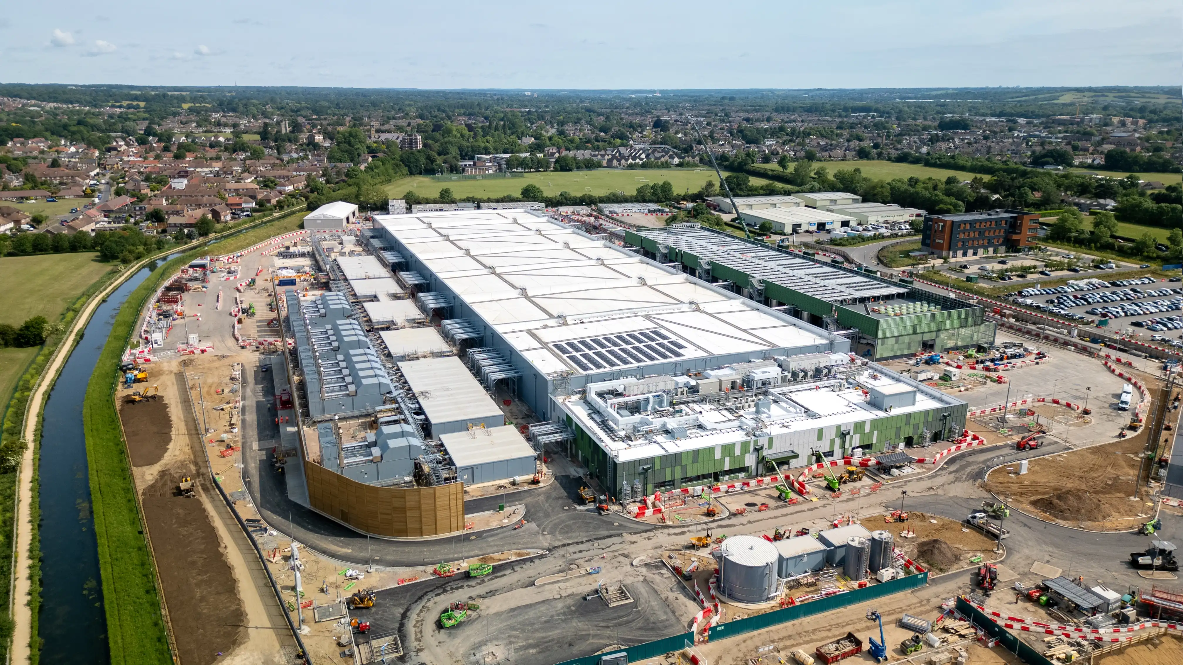An aerial shot of a data centre being built. It shows a long single warehouse with many building beside it in a vast landscape