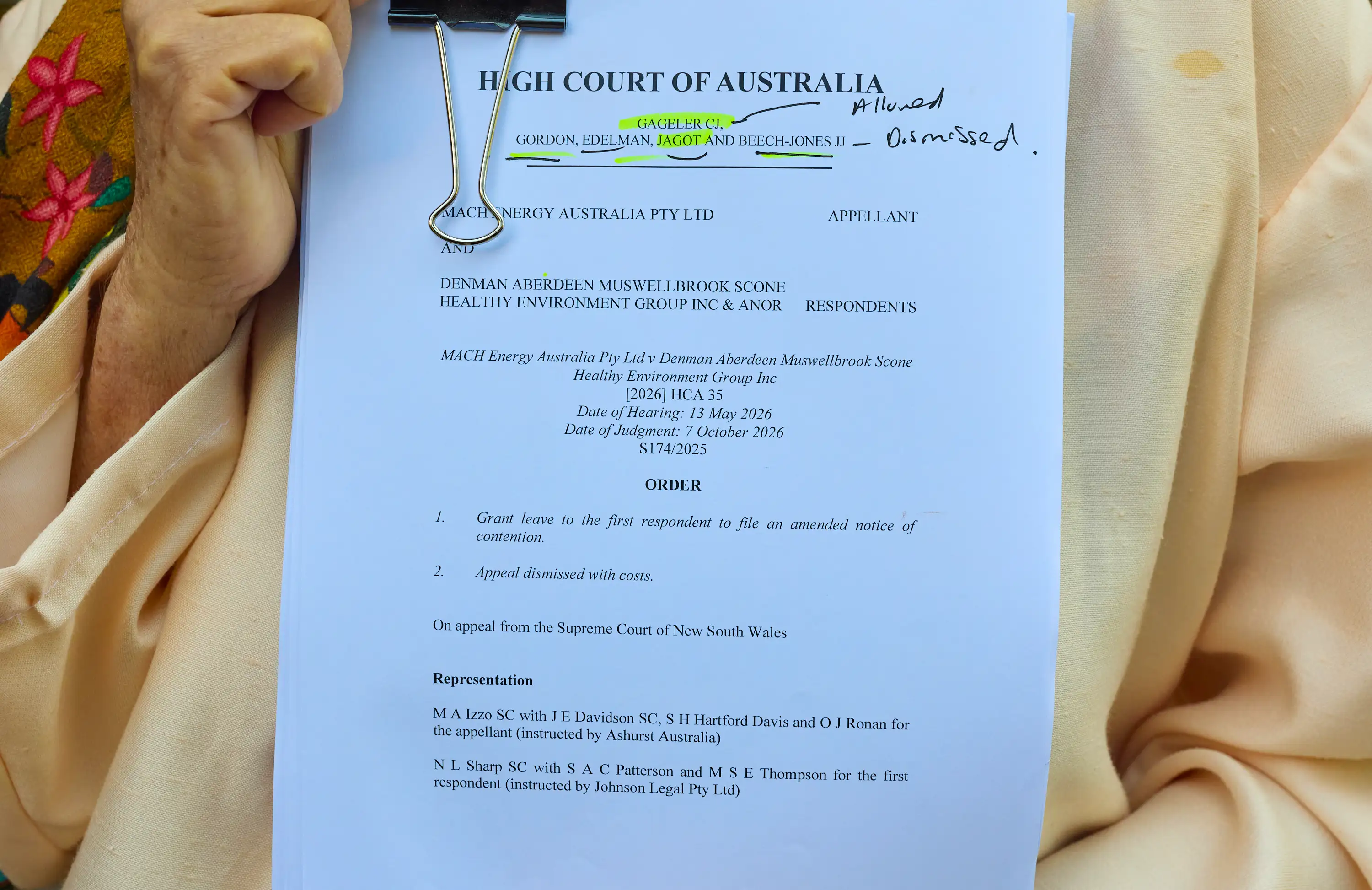 A close-up of a person holding documents relating to the ruling in the case of Denman Aberdeen Muswellbrook Scone Healthy Environment Group suing coal miner MACH Energy Australia Pty Ltd